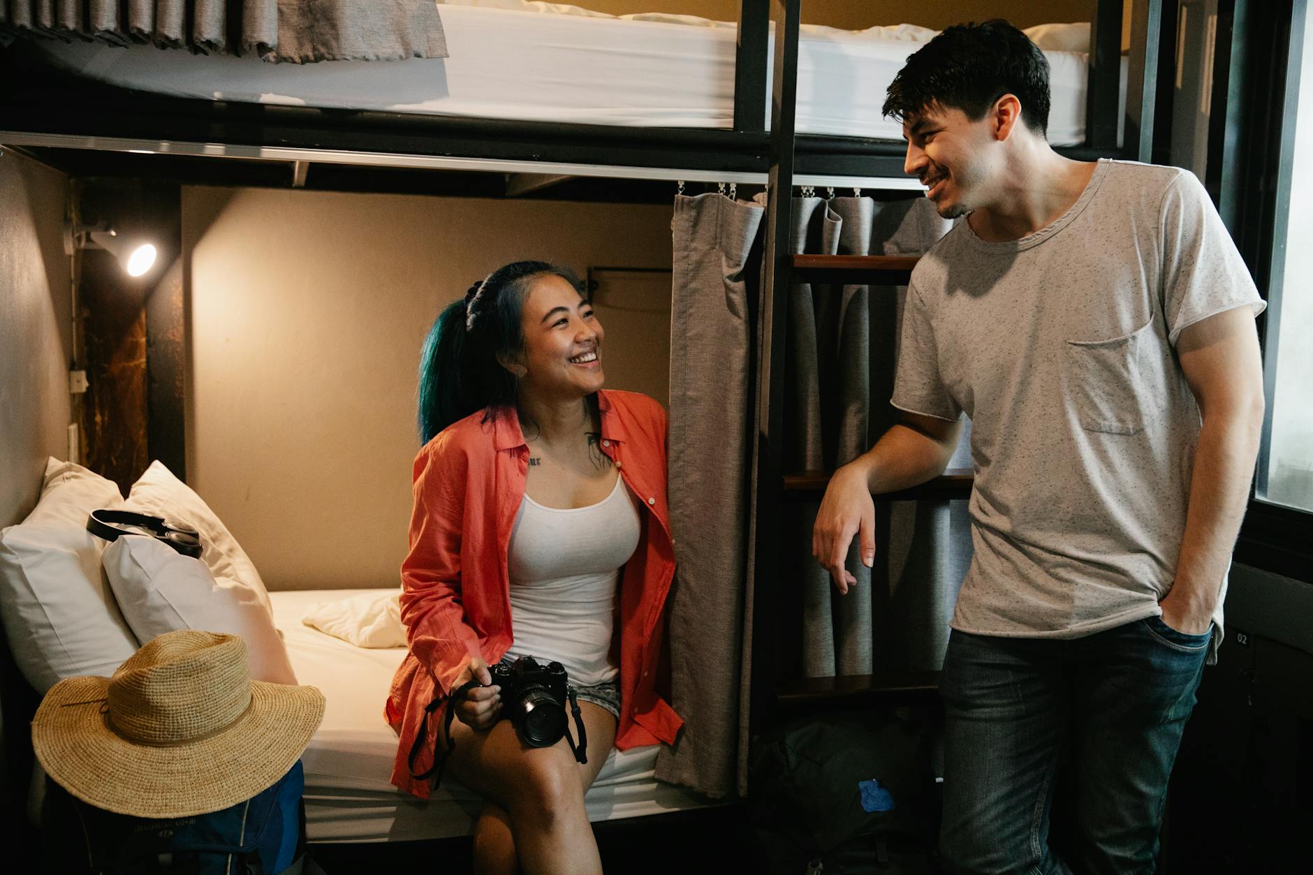 Cheerful young couple enjoying leisure time in a cozy hostel dorm room, capturing travel memories. - declutter relationship baggage