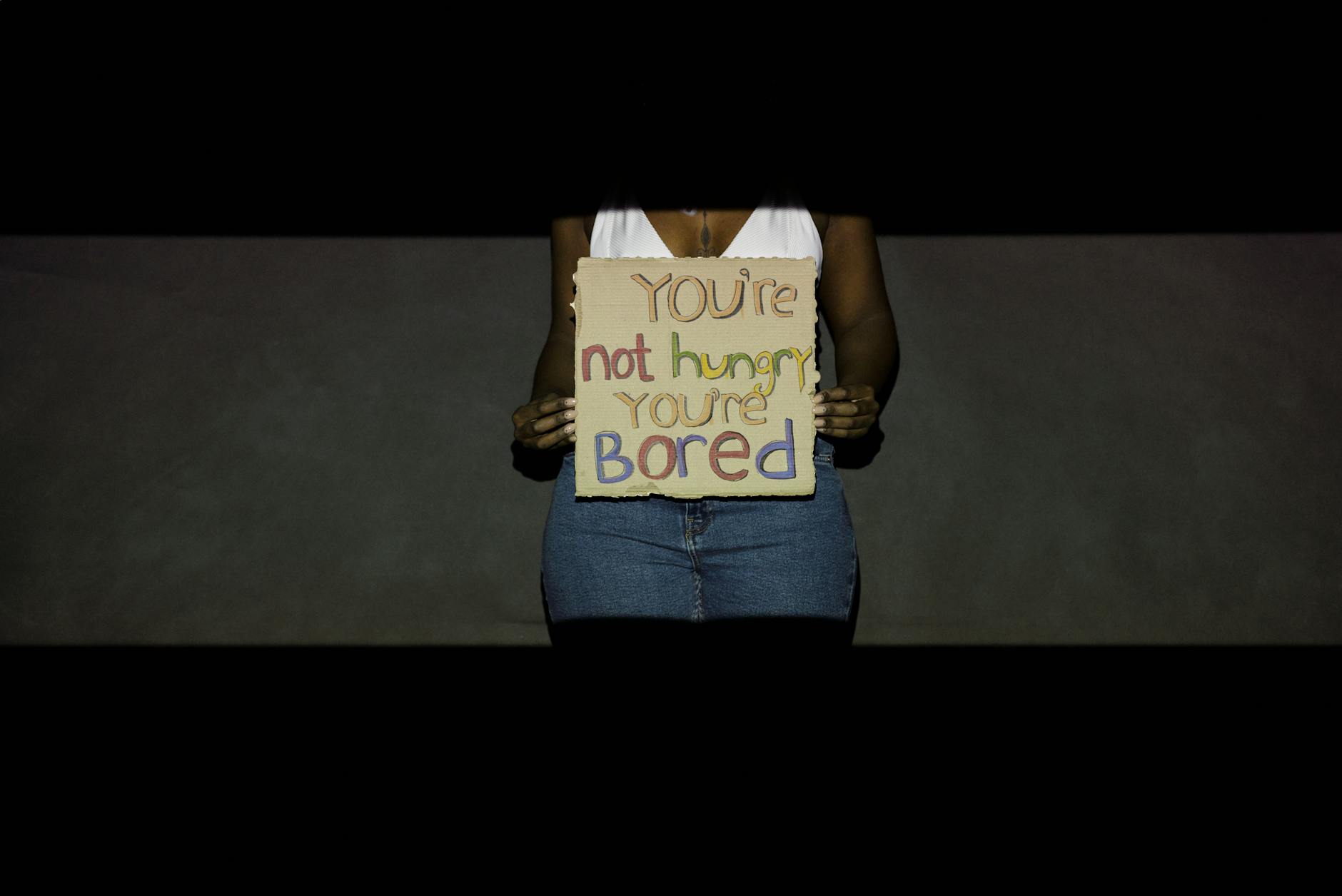 Woman holding cardboard sign with motivational message against overeating. - declutter your mind