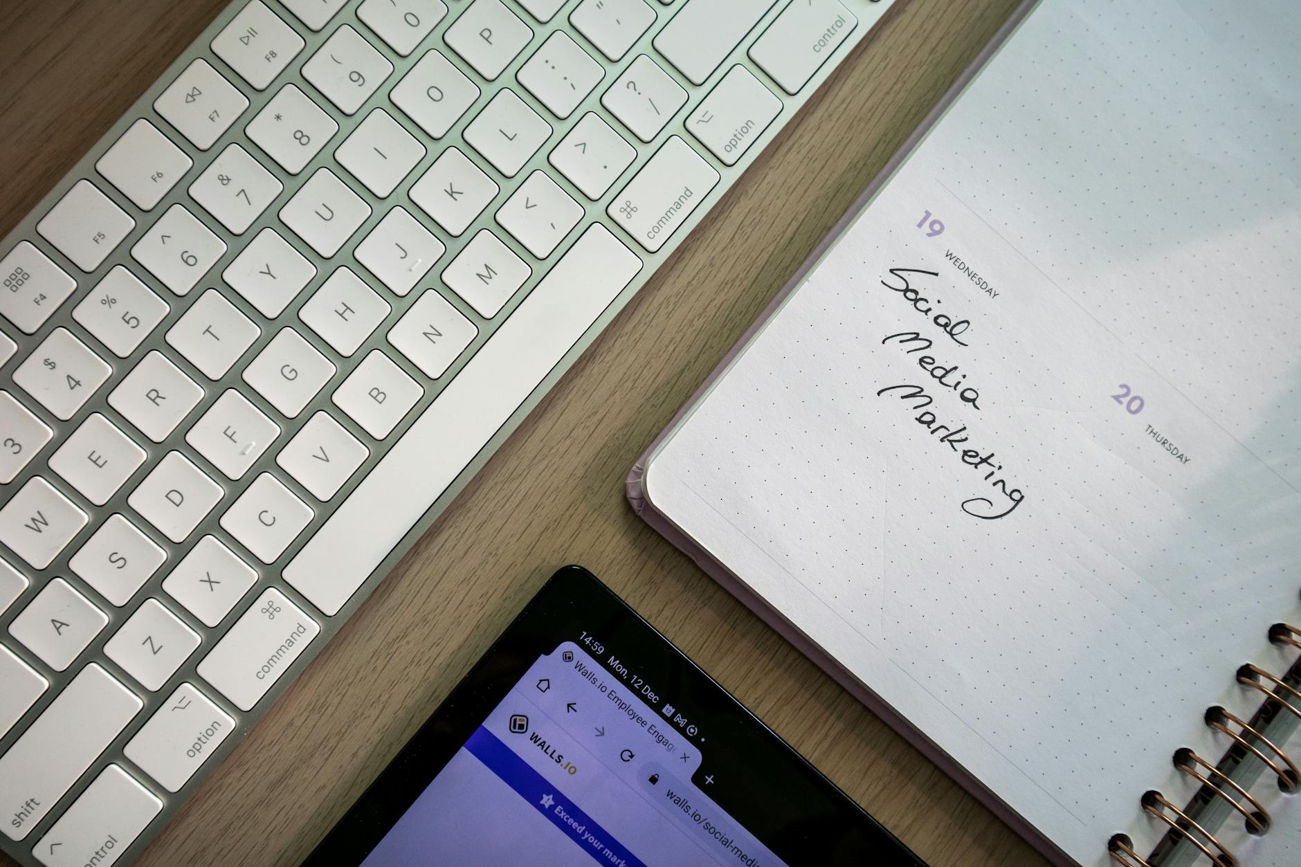 Top view of keyboard, planner with social media marketing note, and tablet on a desk. - effective communication spring plans