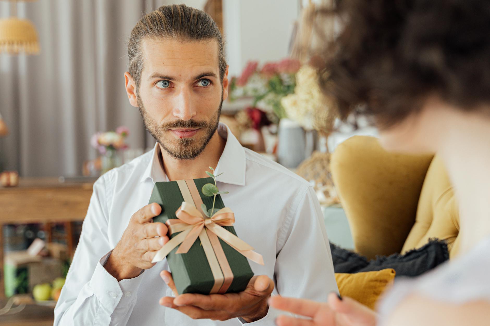 A thoughtful moment captured as a man presents a gift in a cozy indoor setting. - express gratitude relationships