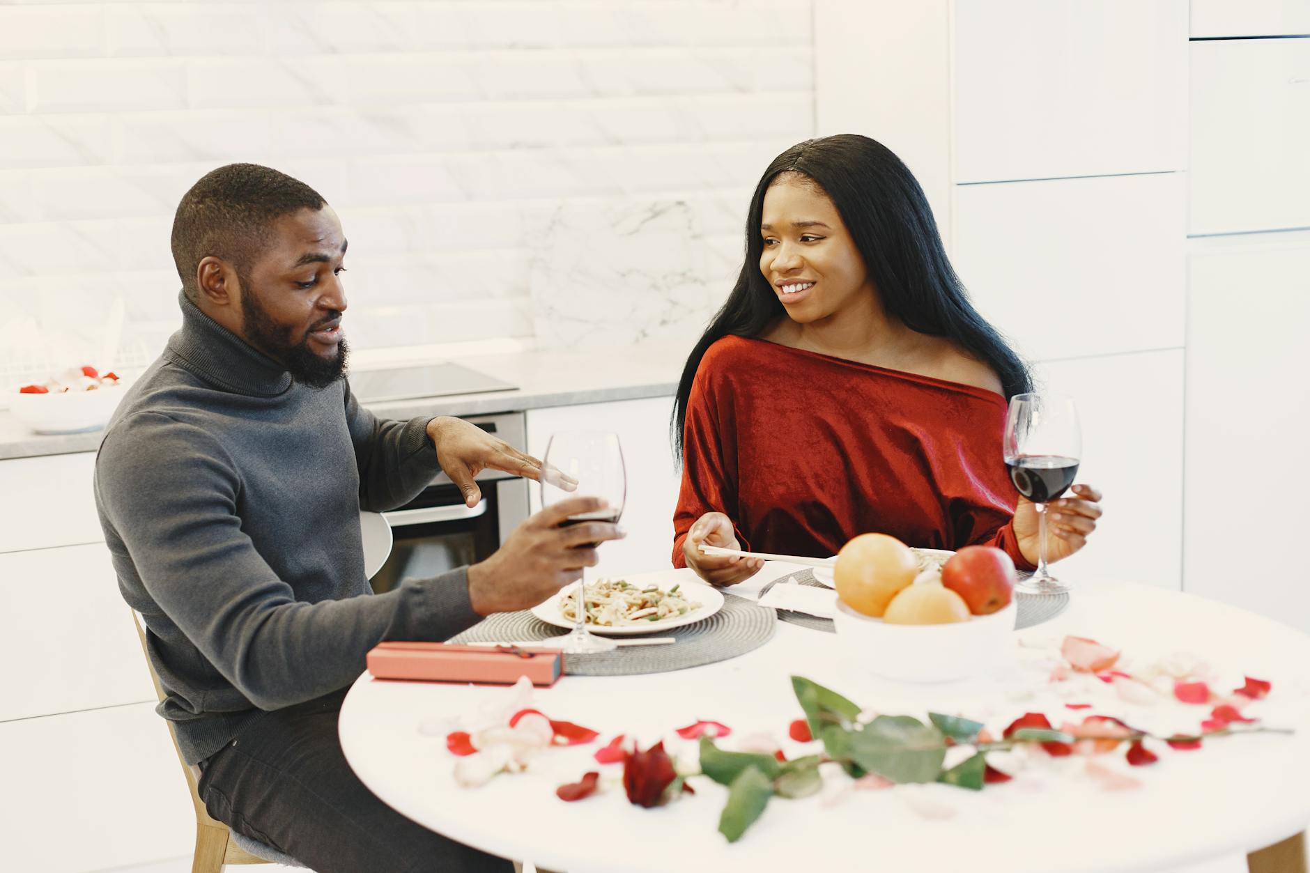 A couple enjoys a romantic dinner with wine and roses in a cozy setting. - express gratitude relationships