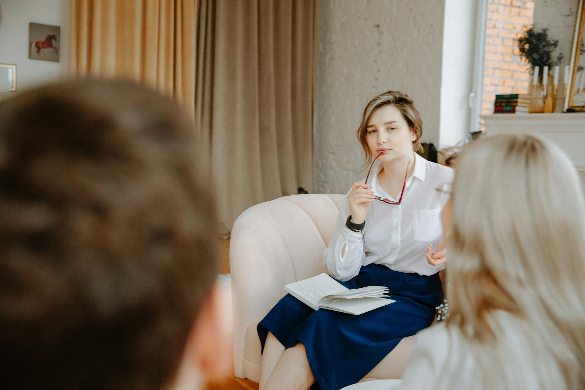 Counselor in a therapy session, attentively listening to clients indoors. - find a therapist