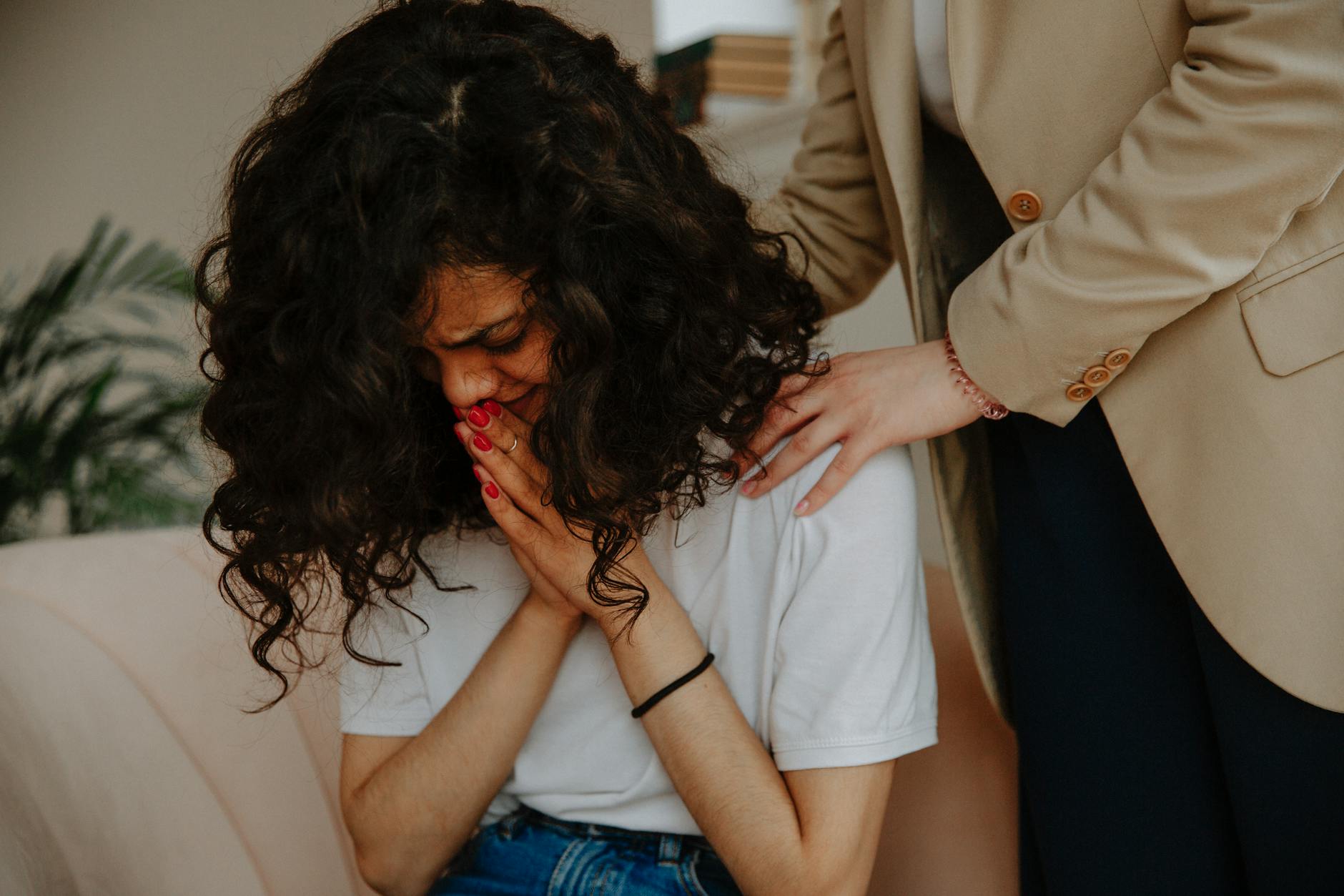 A young woman receiving comforting and emotional support during a therapy session. - what is gaslighting