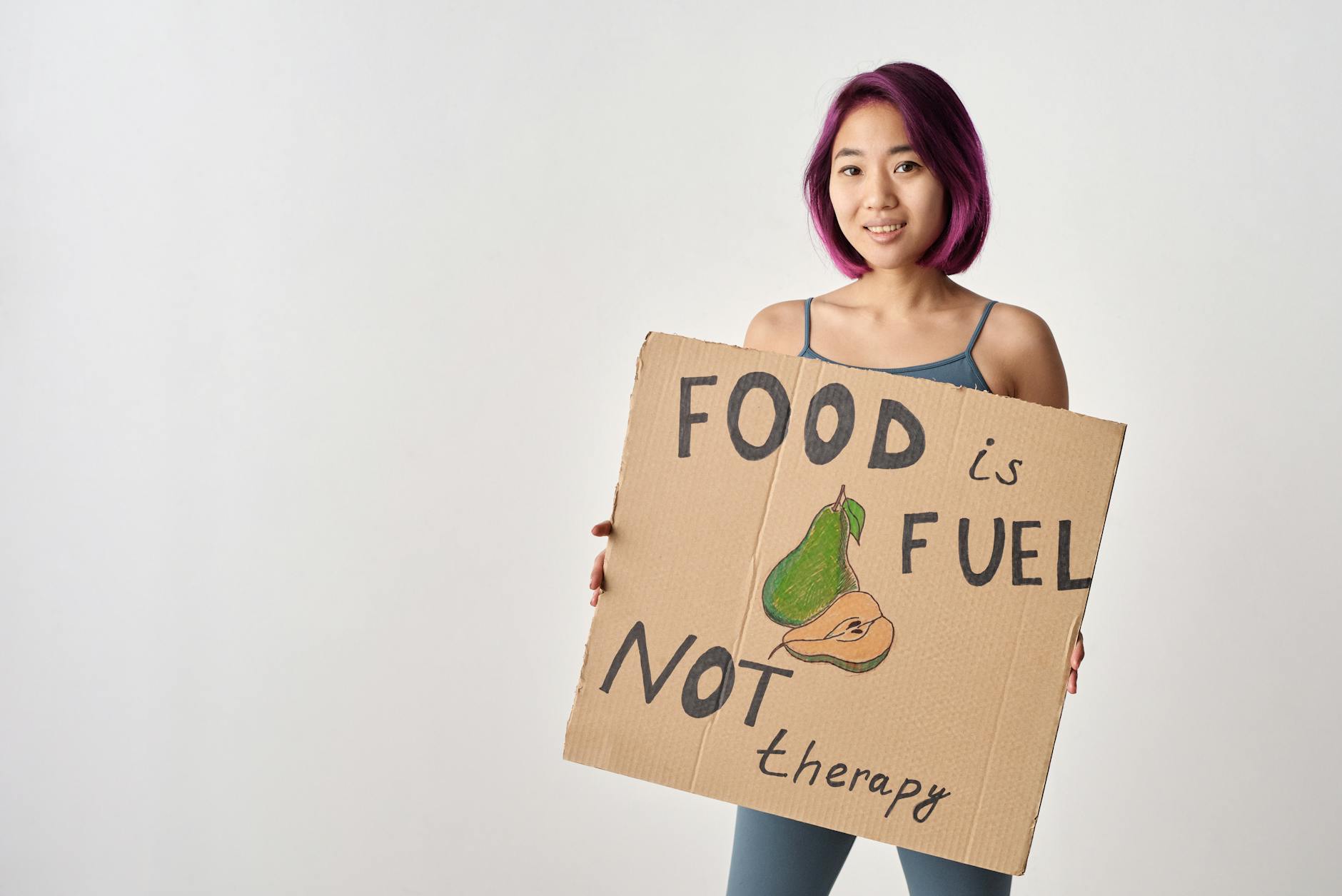 Asian woman holding a sign that states 'Food is Fuel, Not Therapy,' highlighting a healthy lifestyle message. - healthy relationship signs