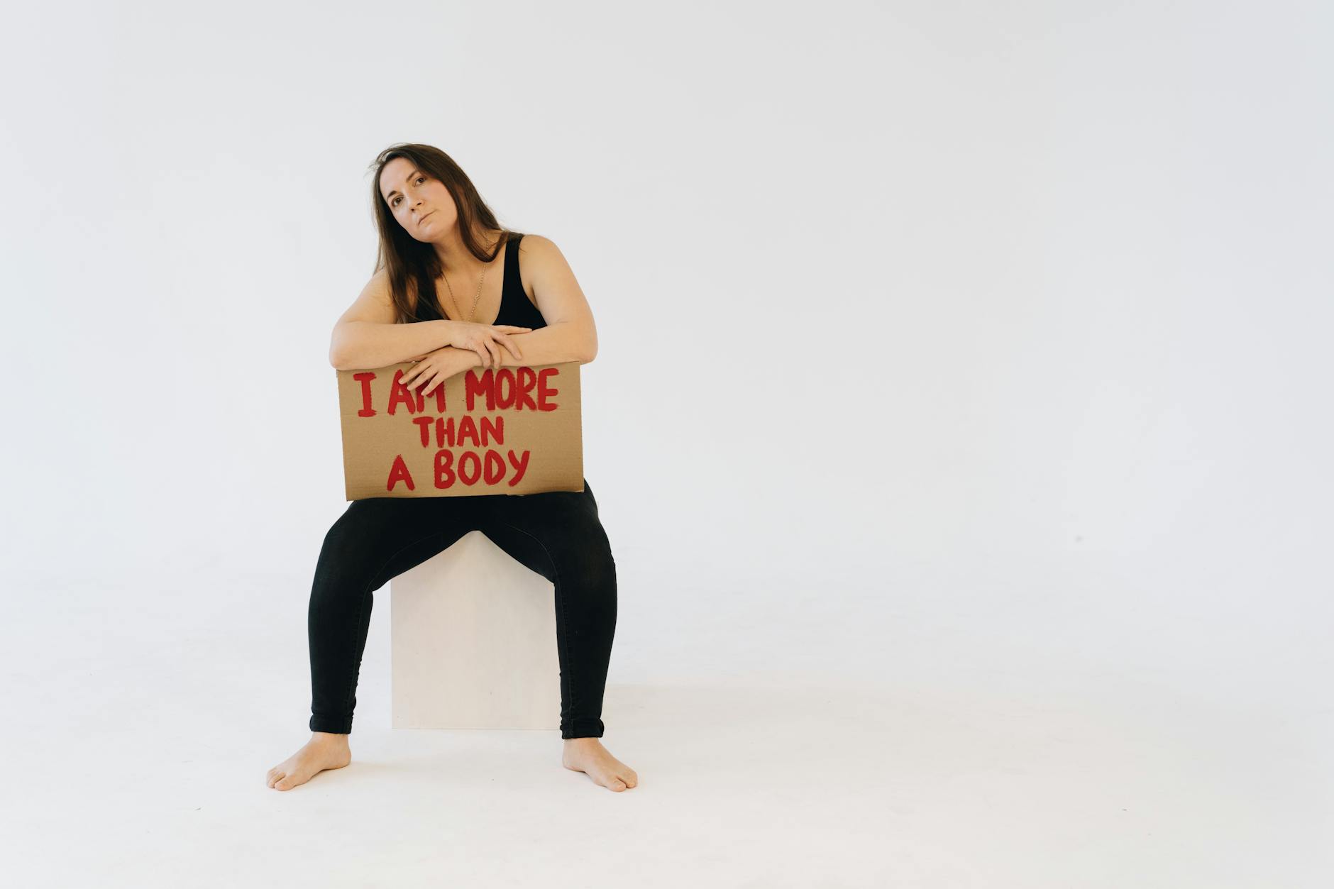 Woman holding 'I am more than a body' sign, promoting empowerment and equality. - i feel statements