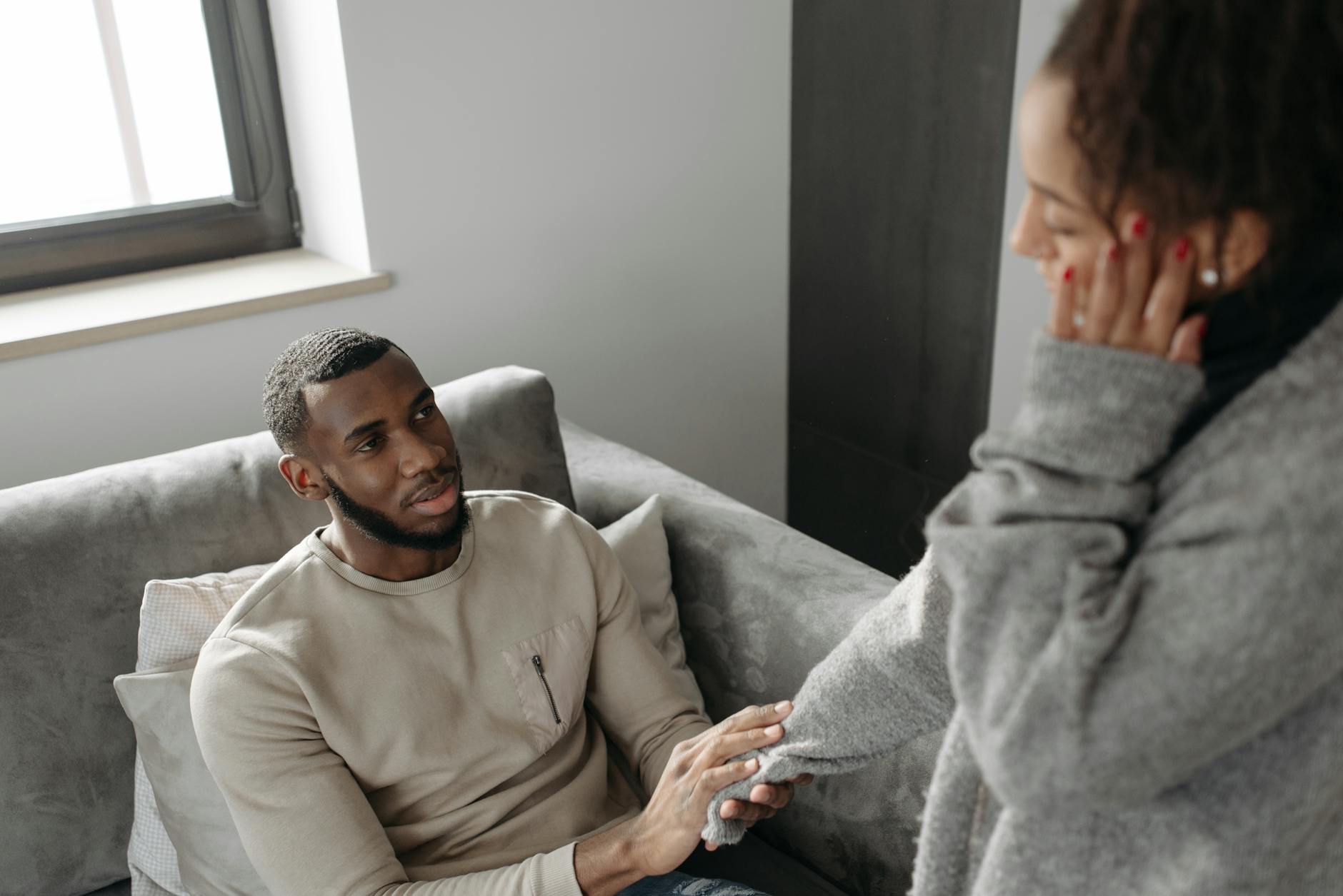 A man sitting on a sofa comforting a woman. Emotional support scene indoors. - partner needs communication