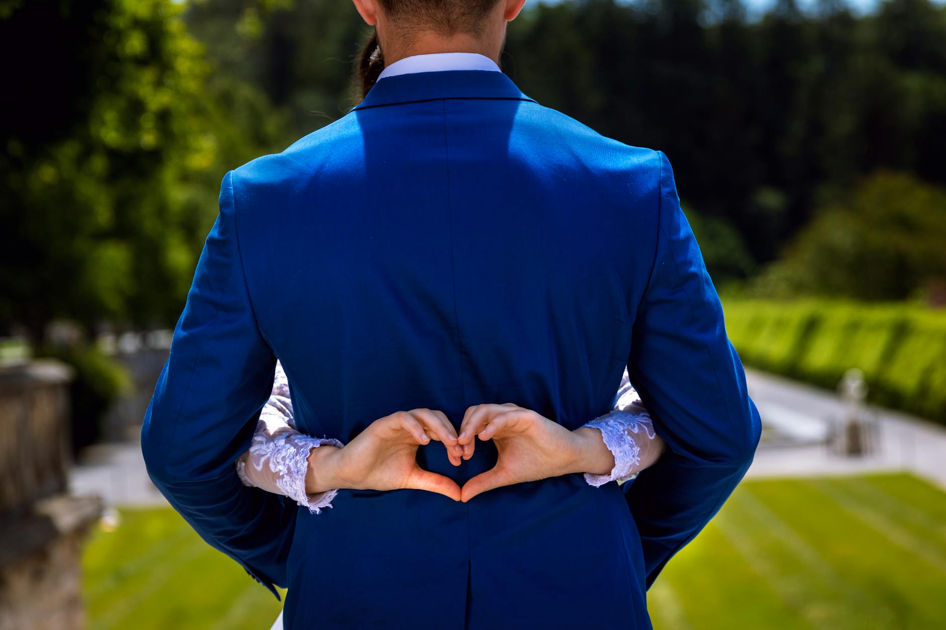 Bride and groom making a heart shape with hands, symbolizing love in an outdoor setting. - rekindle marital intimacy