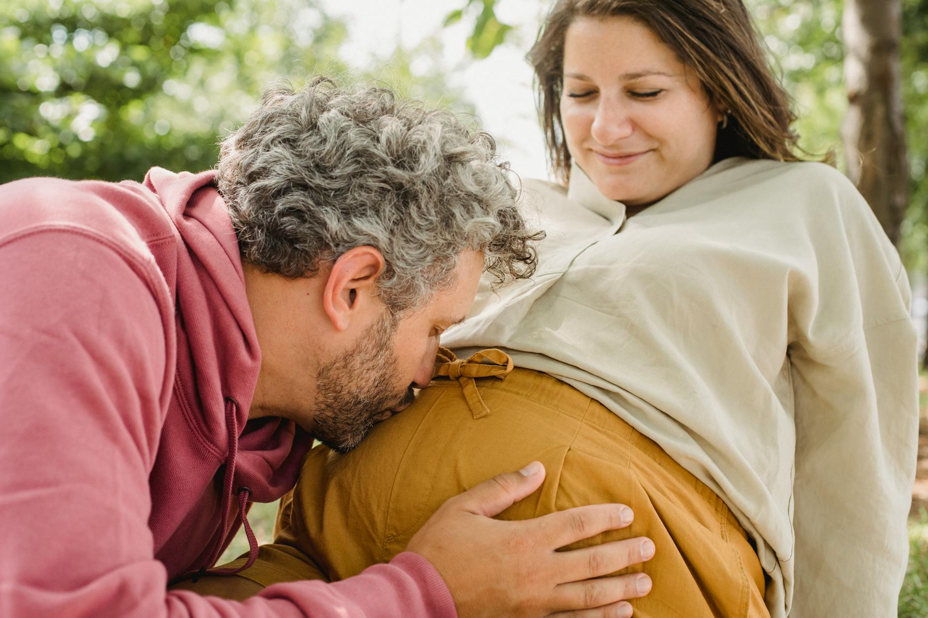 A loving couple sharing a tender moment outdoors during pregnancy. - reset relationship expectations