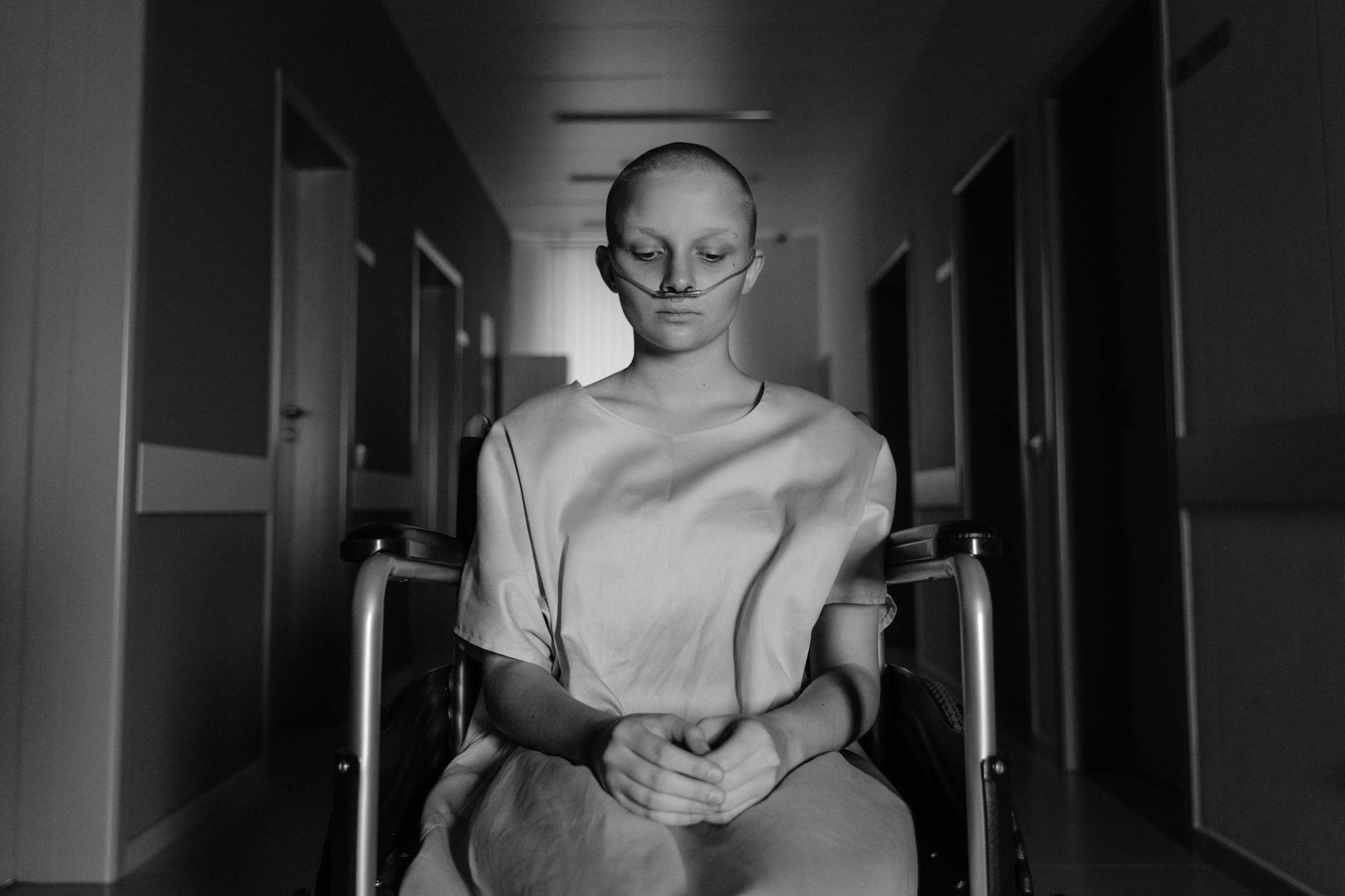 A woman in a wheelchair, deep in thought, in a hospital corridor. - sad spring treatment