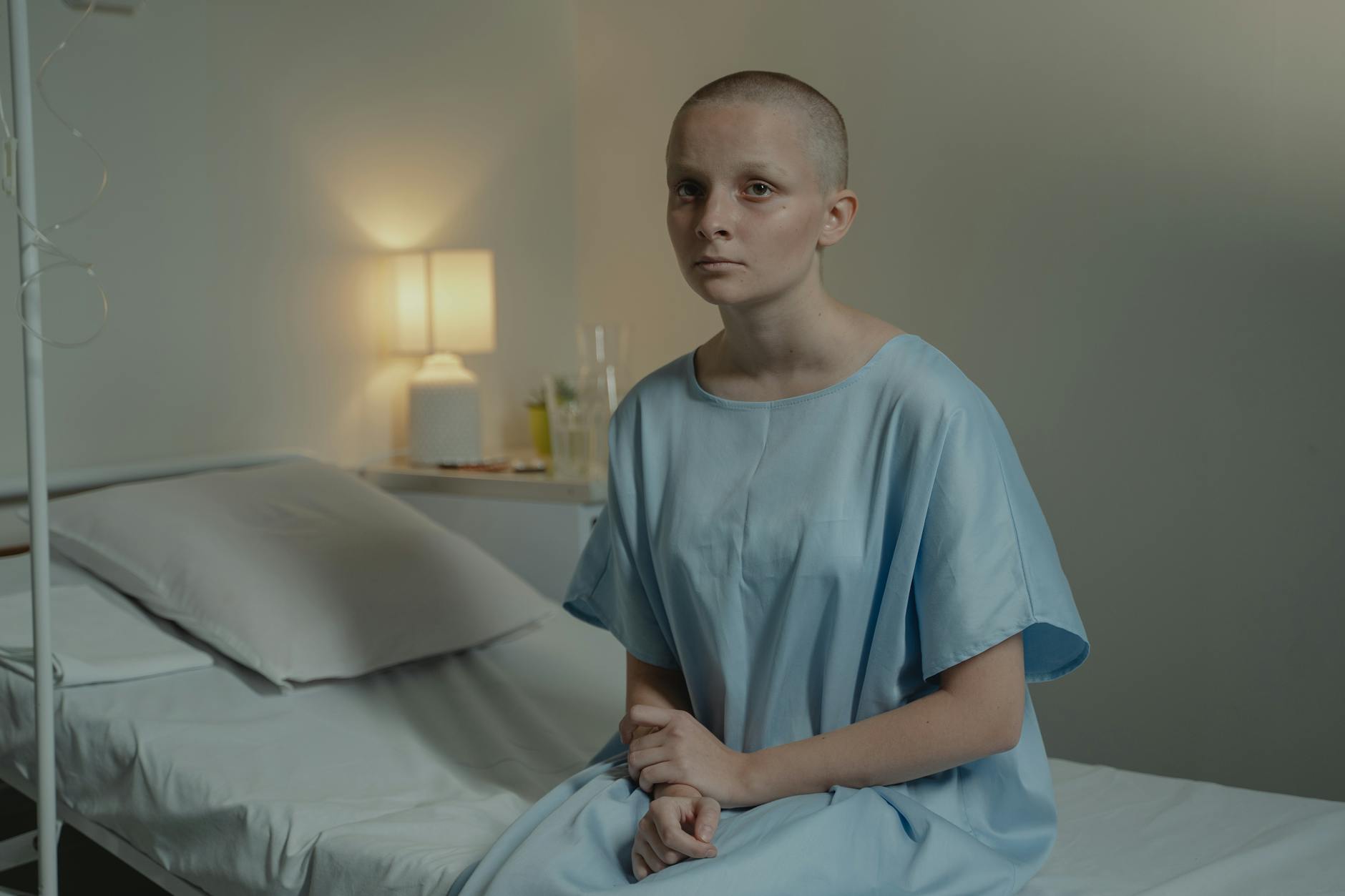 A young patient in a hospital room wearing a blue gown, conveying a calm mood. - sad spring treatment