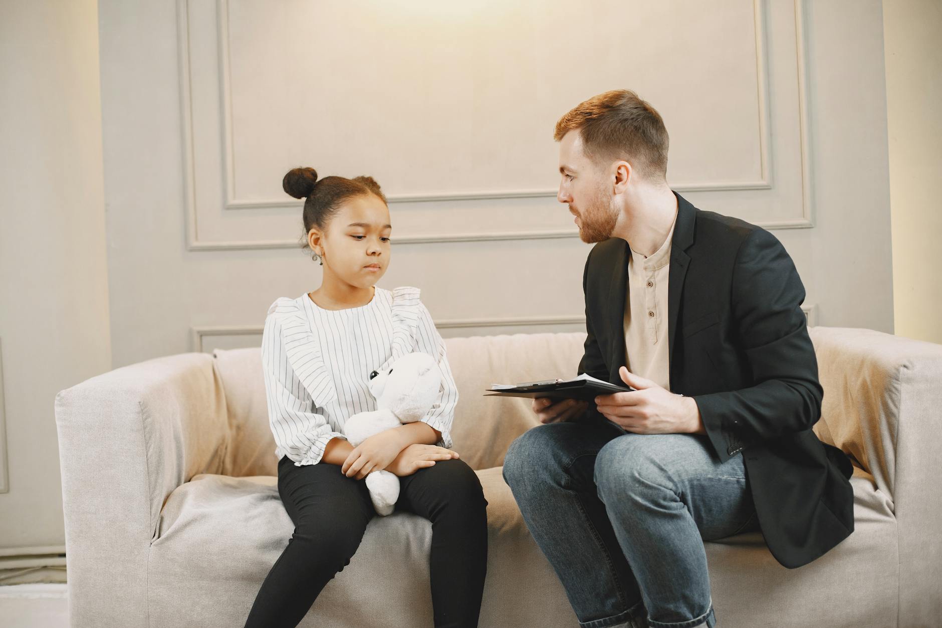 A young girl and a counselor having a therapy session indoors, fostering emotional support. - sadness therapy spring