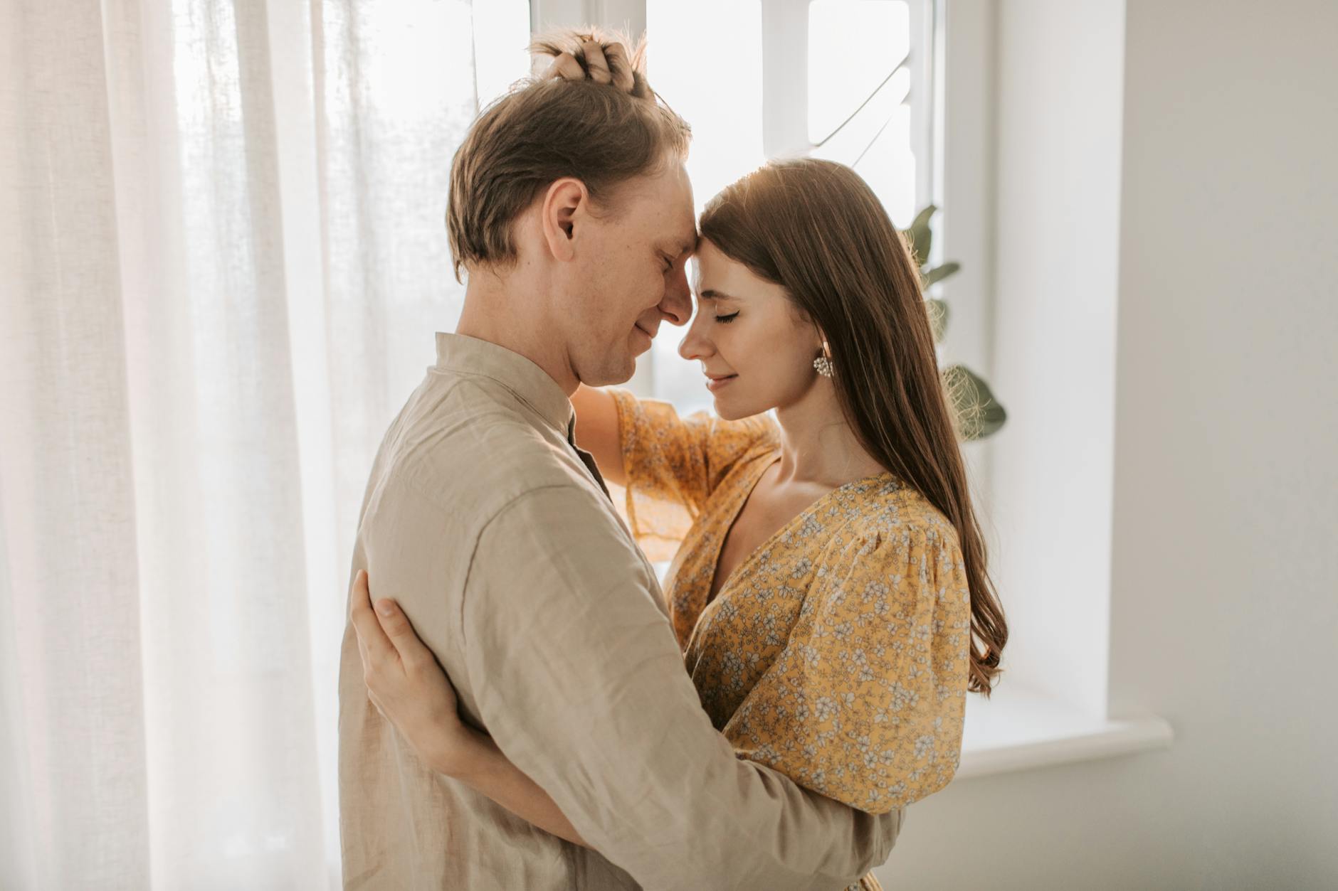 A loving couple embraces in a bright, sunlit room, exuding warmth and togetherness. - secure attachment style