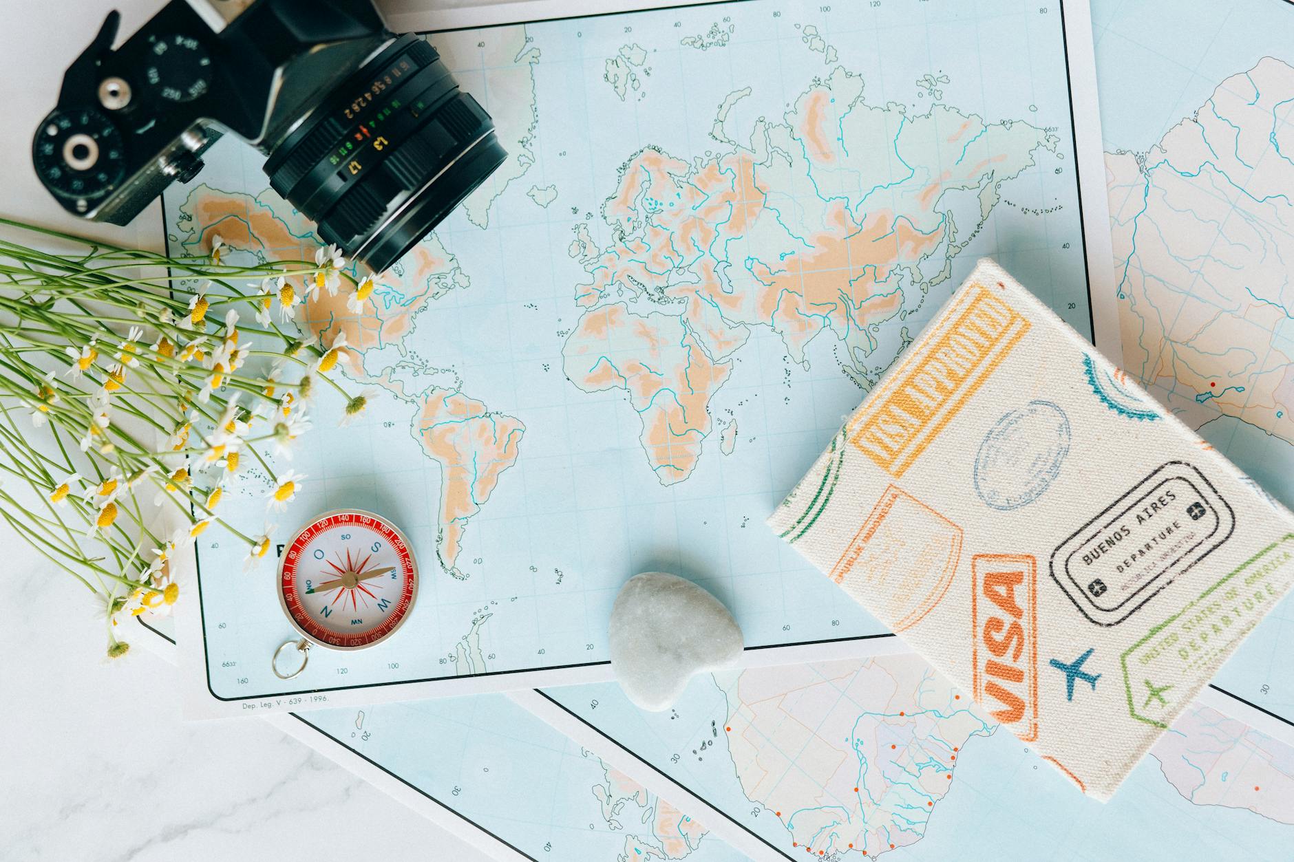 Flat lay of travel essentials: maps, camera, compass, and travel journal for planning adventures. - self-compassion guide