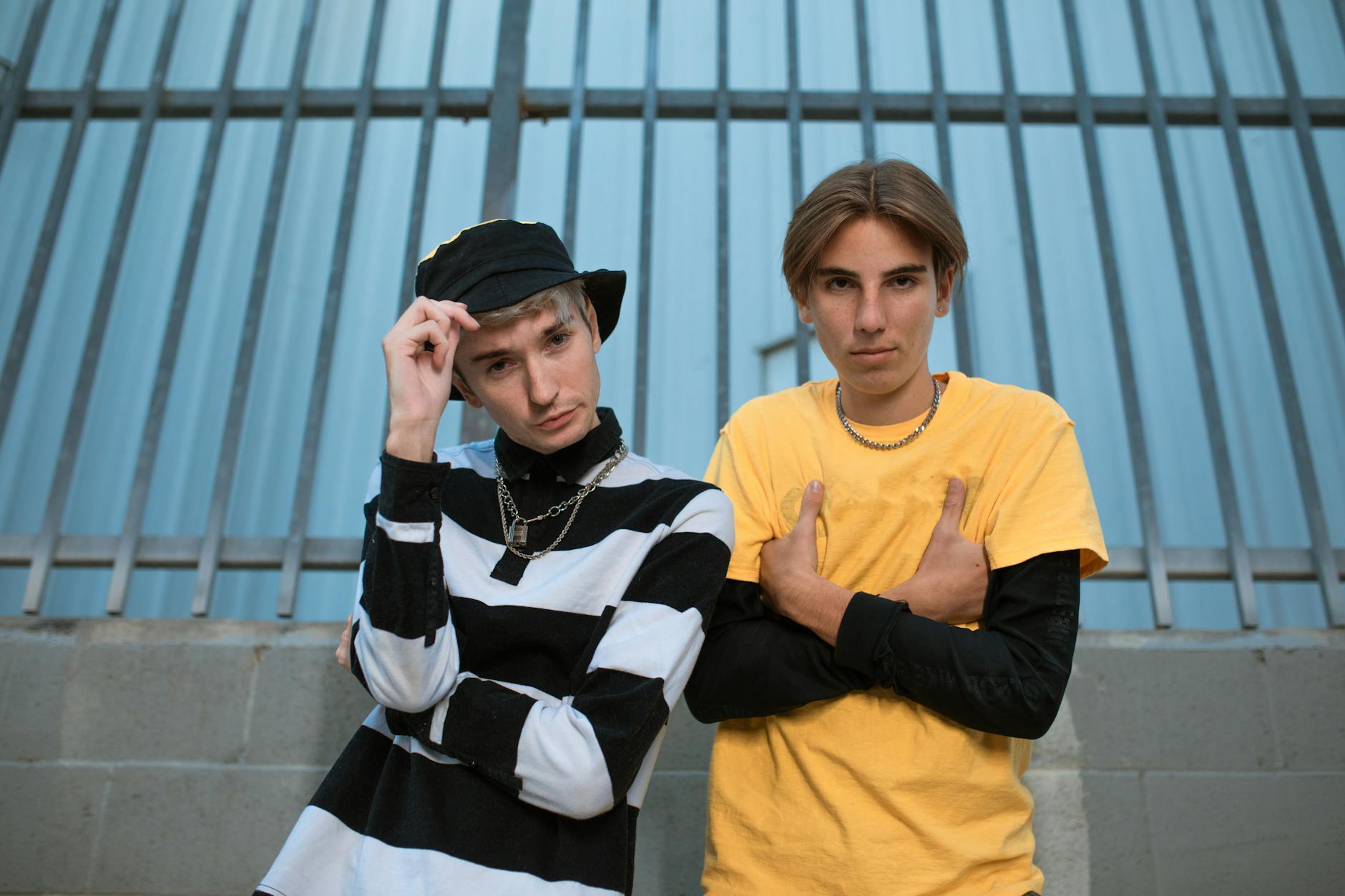 Two trendy teenagers posing in casual outfits against a metal fence background. - social media effects on teens