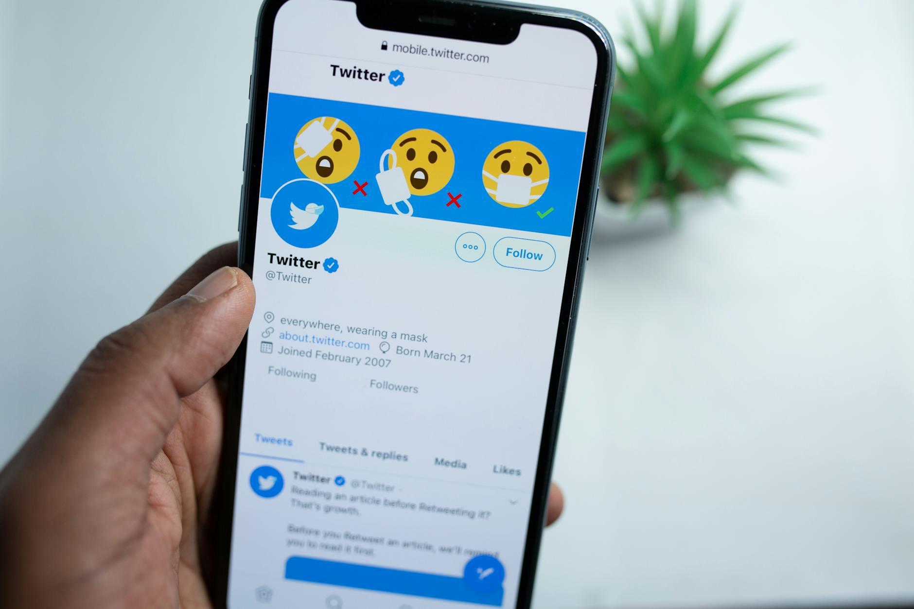 A close-up of a hand holding a smartphone showing a Twitter profile, emphasizing social media engagement. - social media mental health