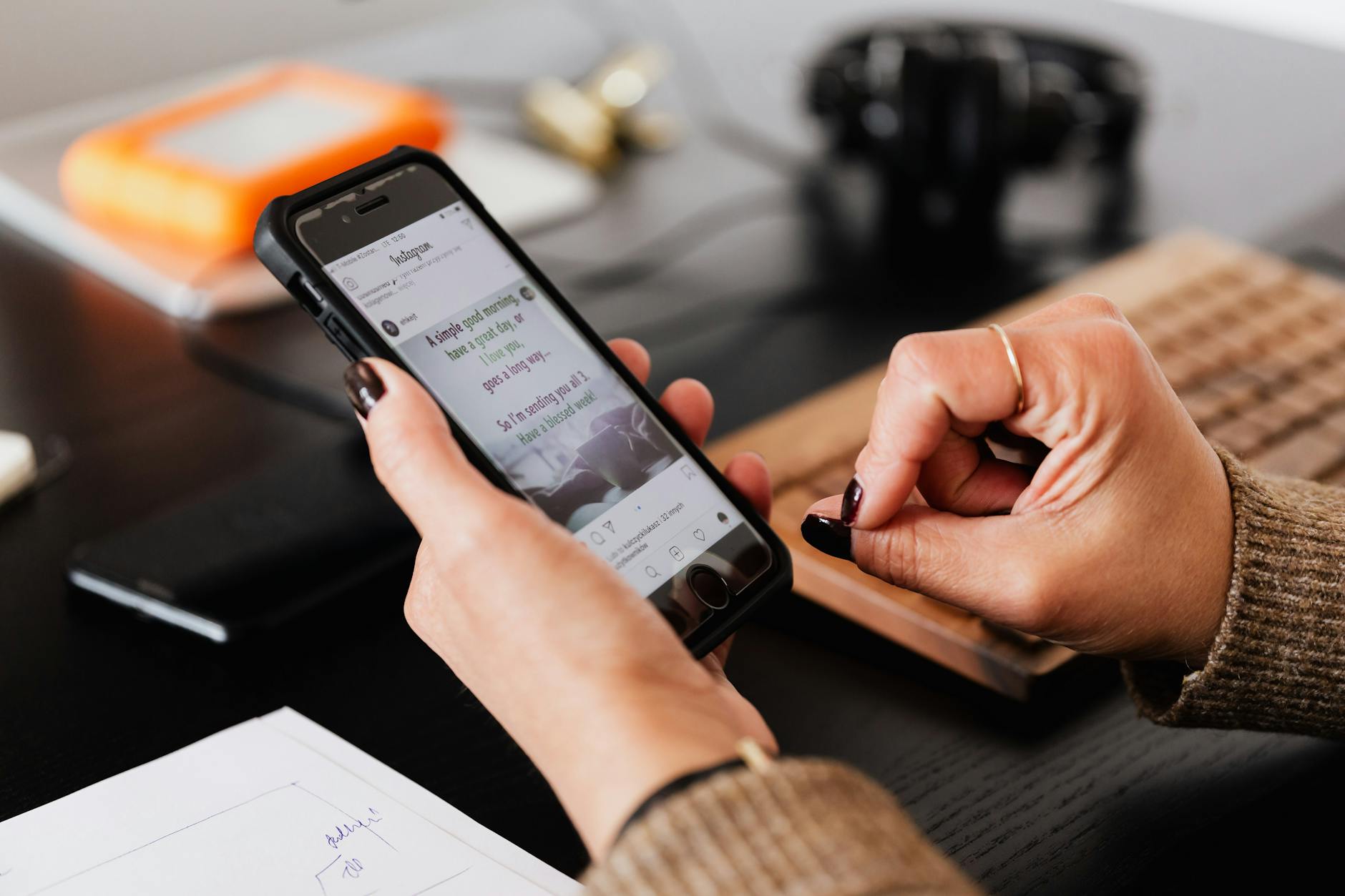 Crop unrecognizable female surfing internet and social nets on modern mobile phone while working at table with keyboard - social media mental health