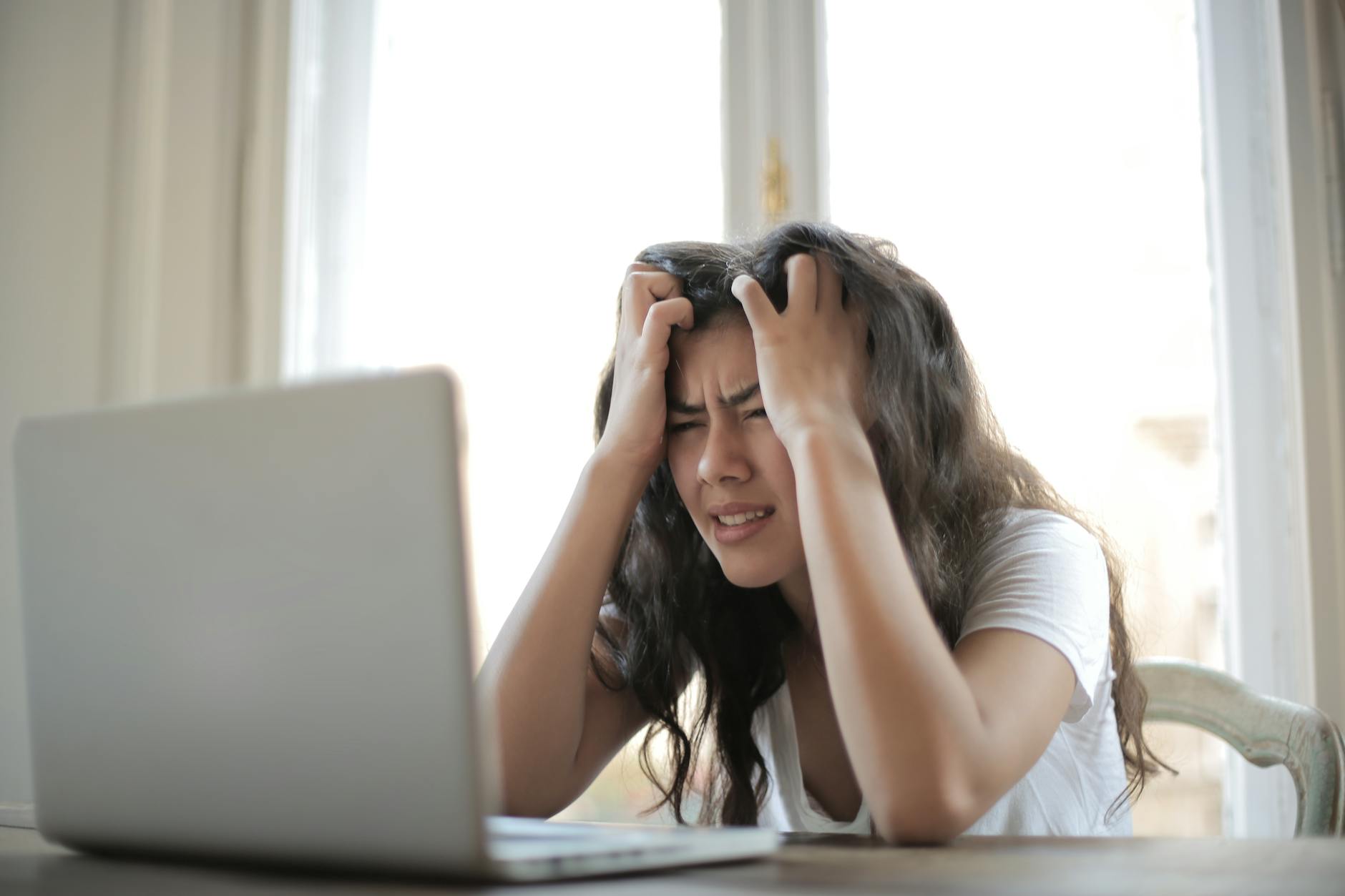 Frustrated woman struggling with remote work stress and digital challenges indoors. - spring anxiety adults