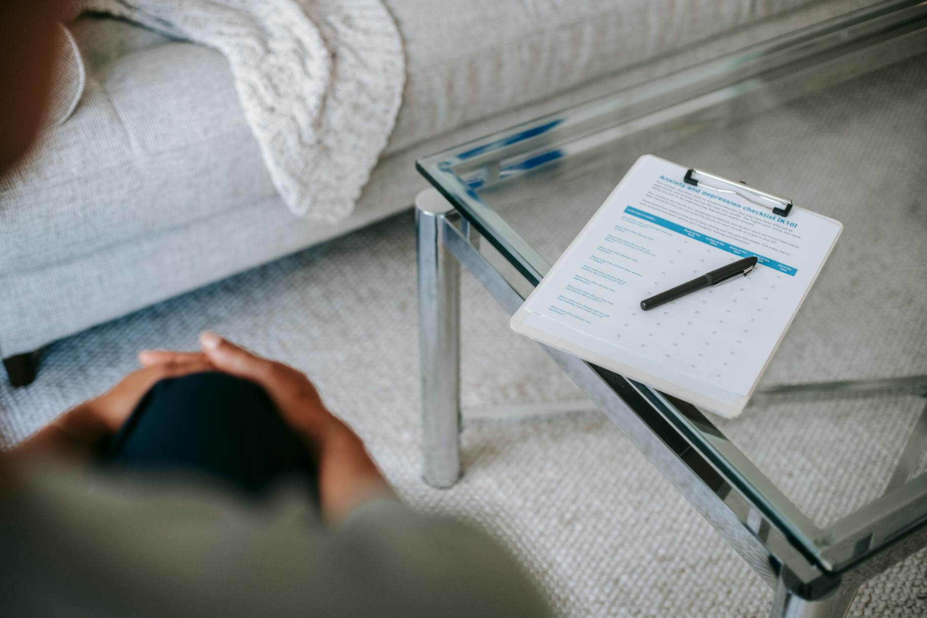 A therapy session setup with a clipboard and anxiety assessment form on a glass table. - spring anxiety help