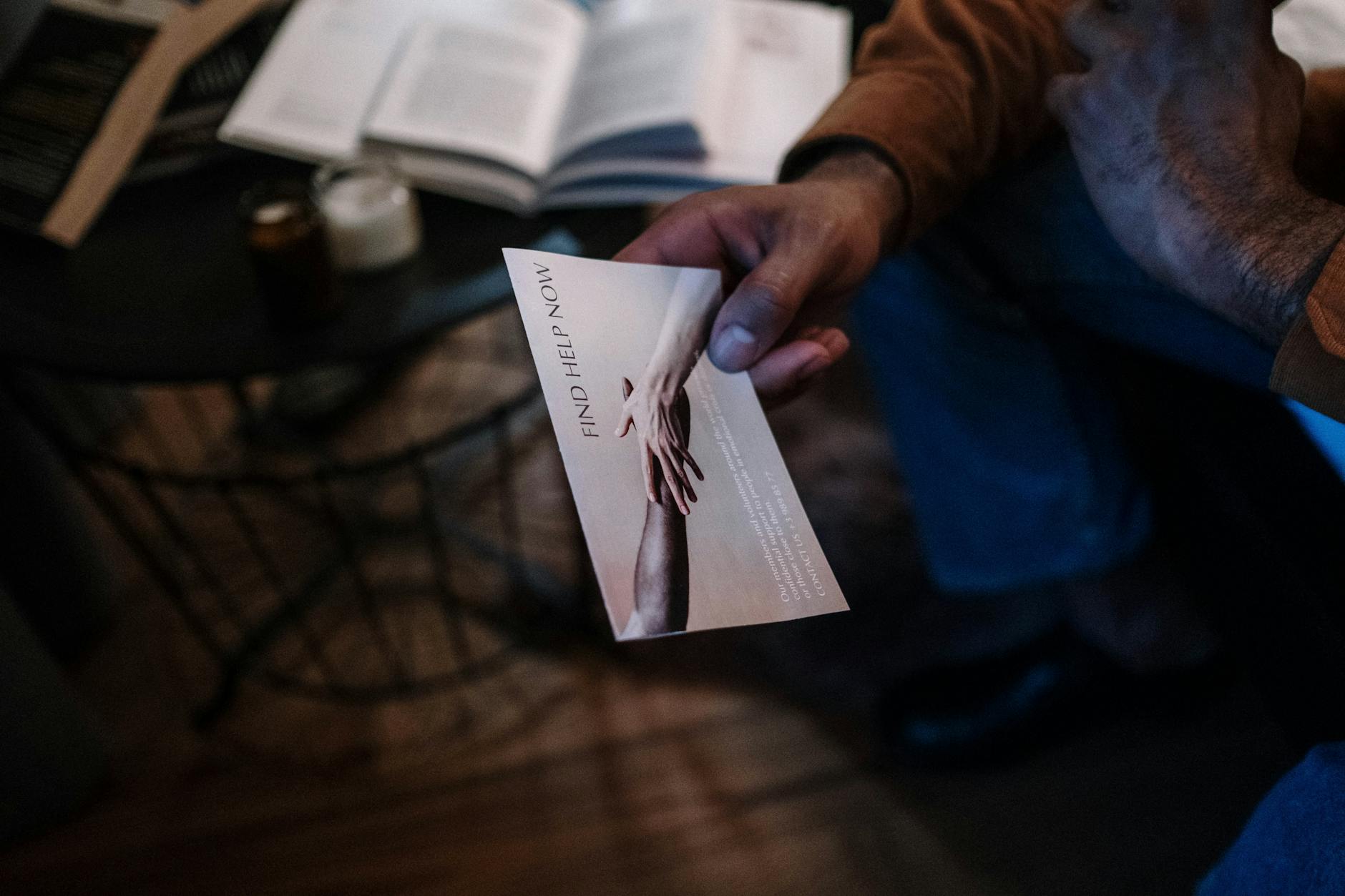 A person holds a help brochure in a cozy indoor setting, symbolizing support and mental health awareness. - spring anxiety help