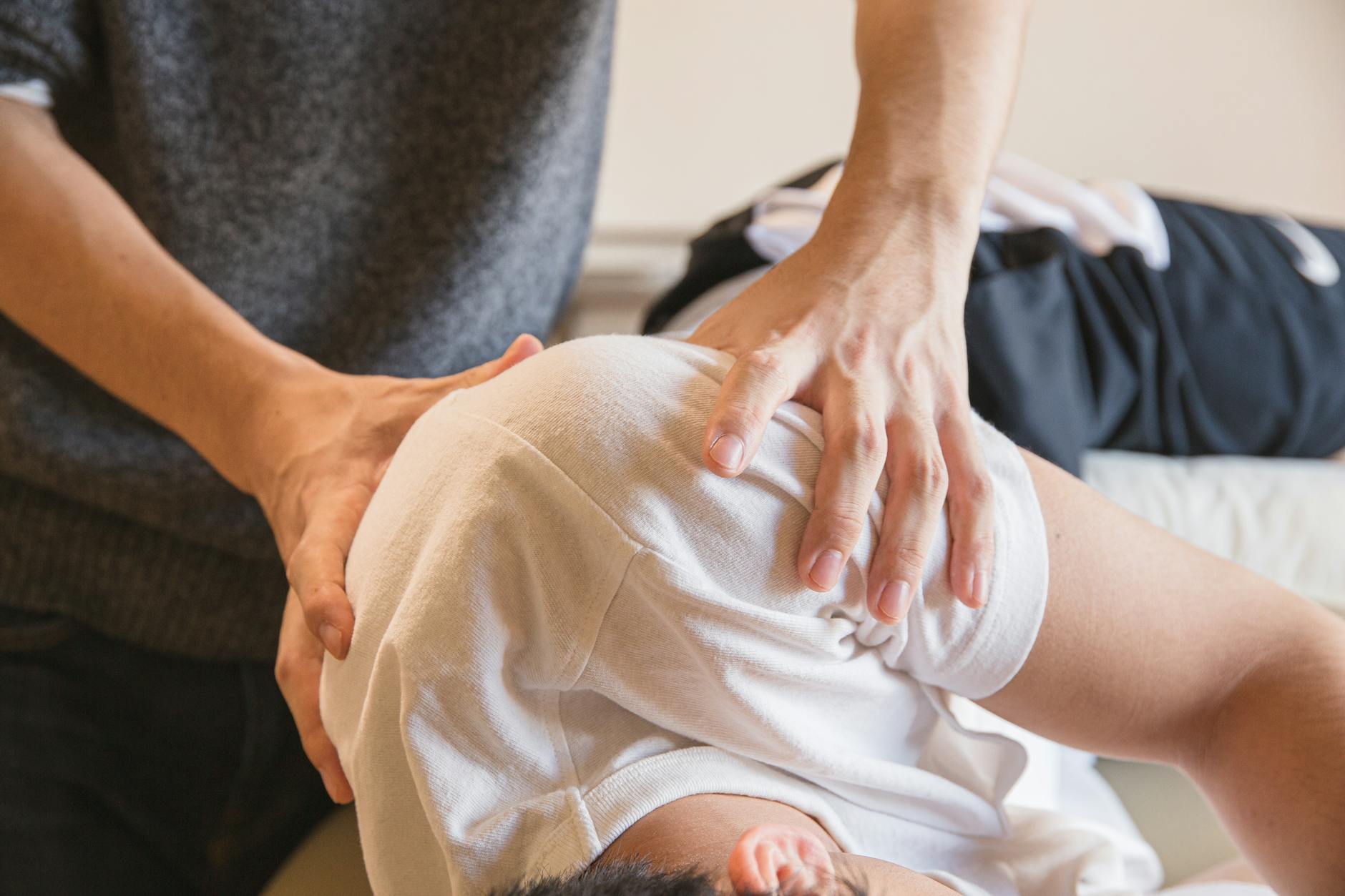 Crop anonymous medical specialist rubbing shoulders of male client lying on couch in medical salon - spring blues therapy