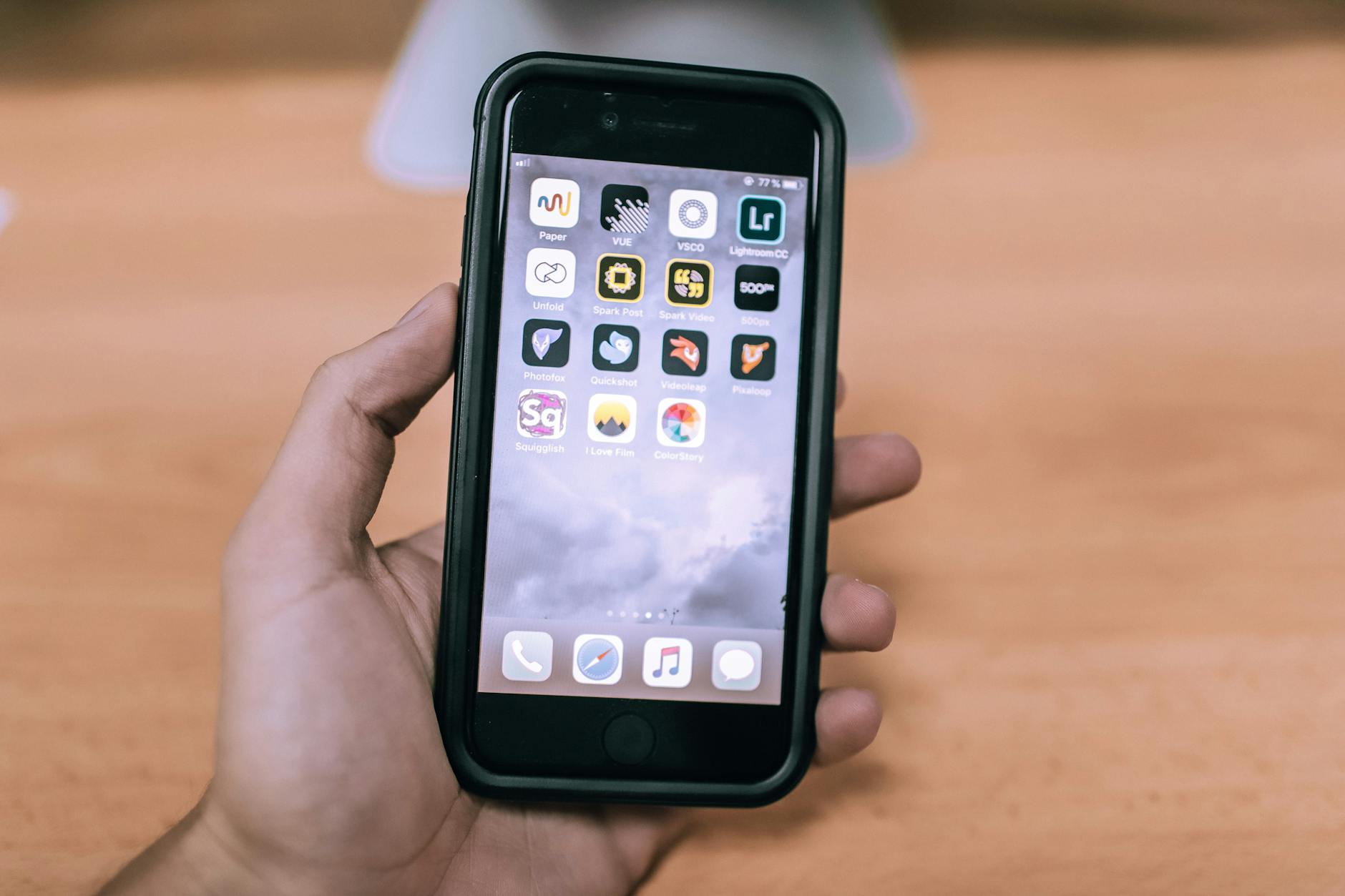 A close-up image of a hand holding a smartphone with various app icons visible on the screen. - spring dating app