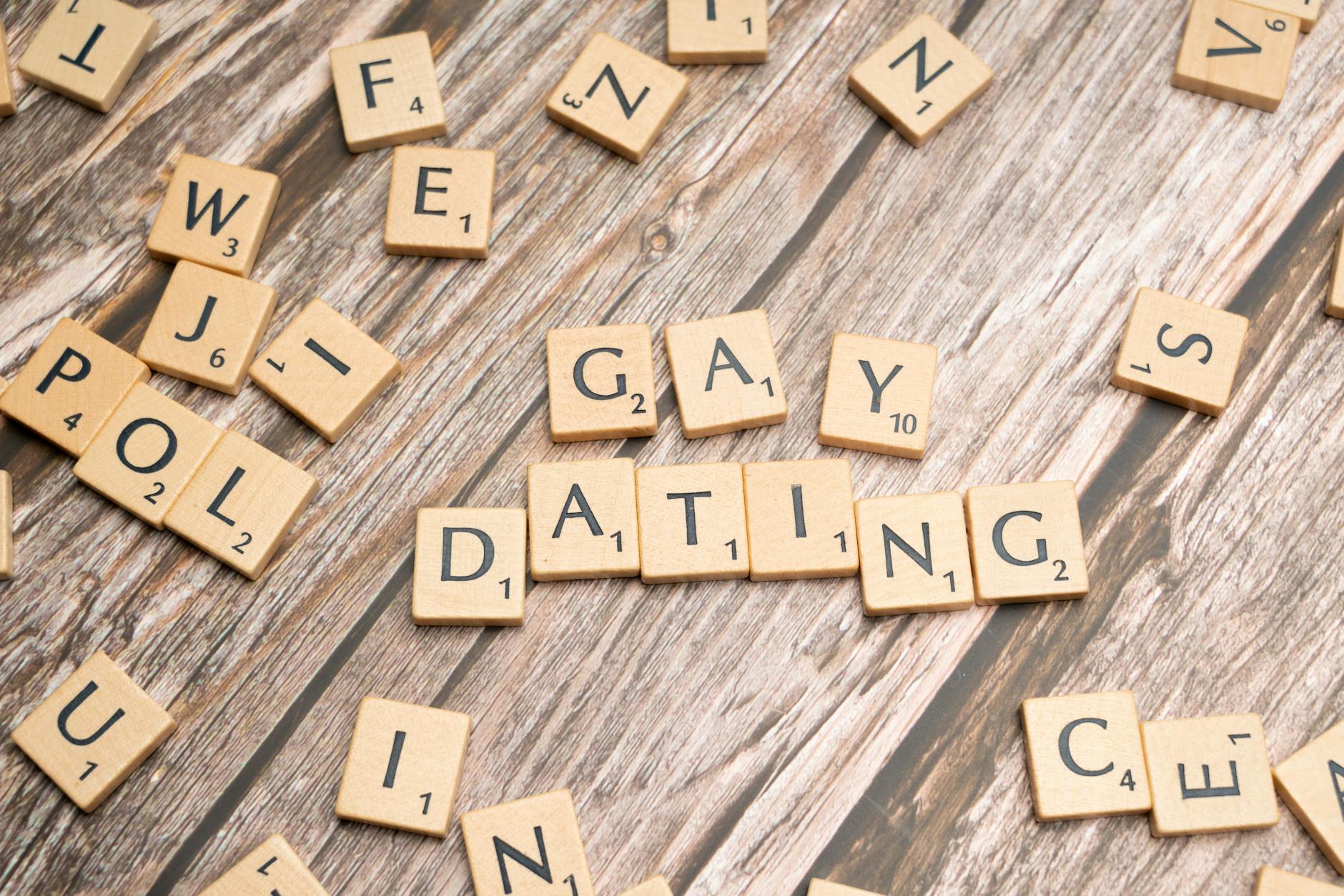 Scrabble tiles spelling 'Gay Dating' on a rustic wooden background, representing LGBTQ themes. - spring dating tips