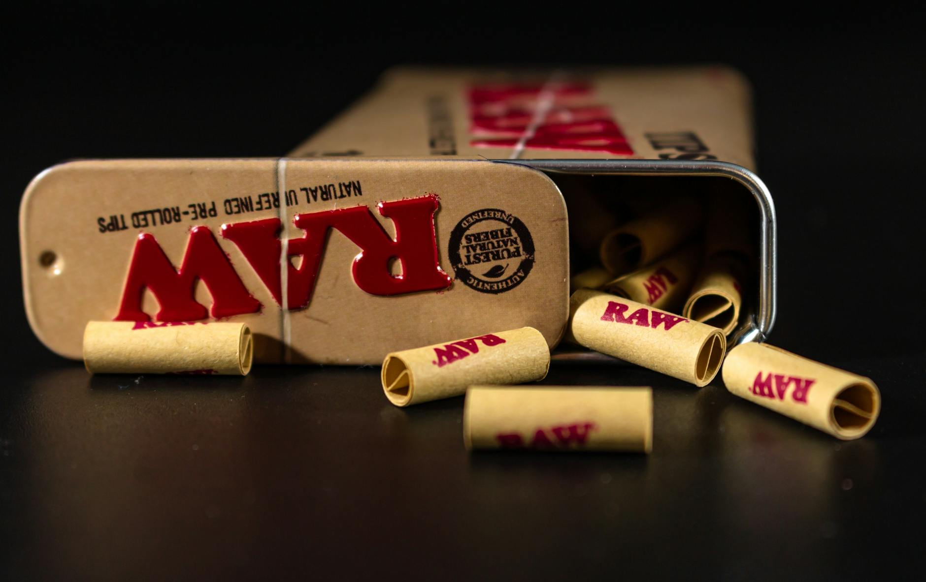 RAW pre-rolled tips spilling from a metal tin on a dark surface, close-up view. - spring dating tips
