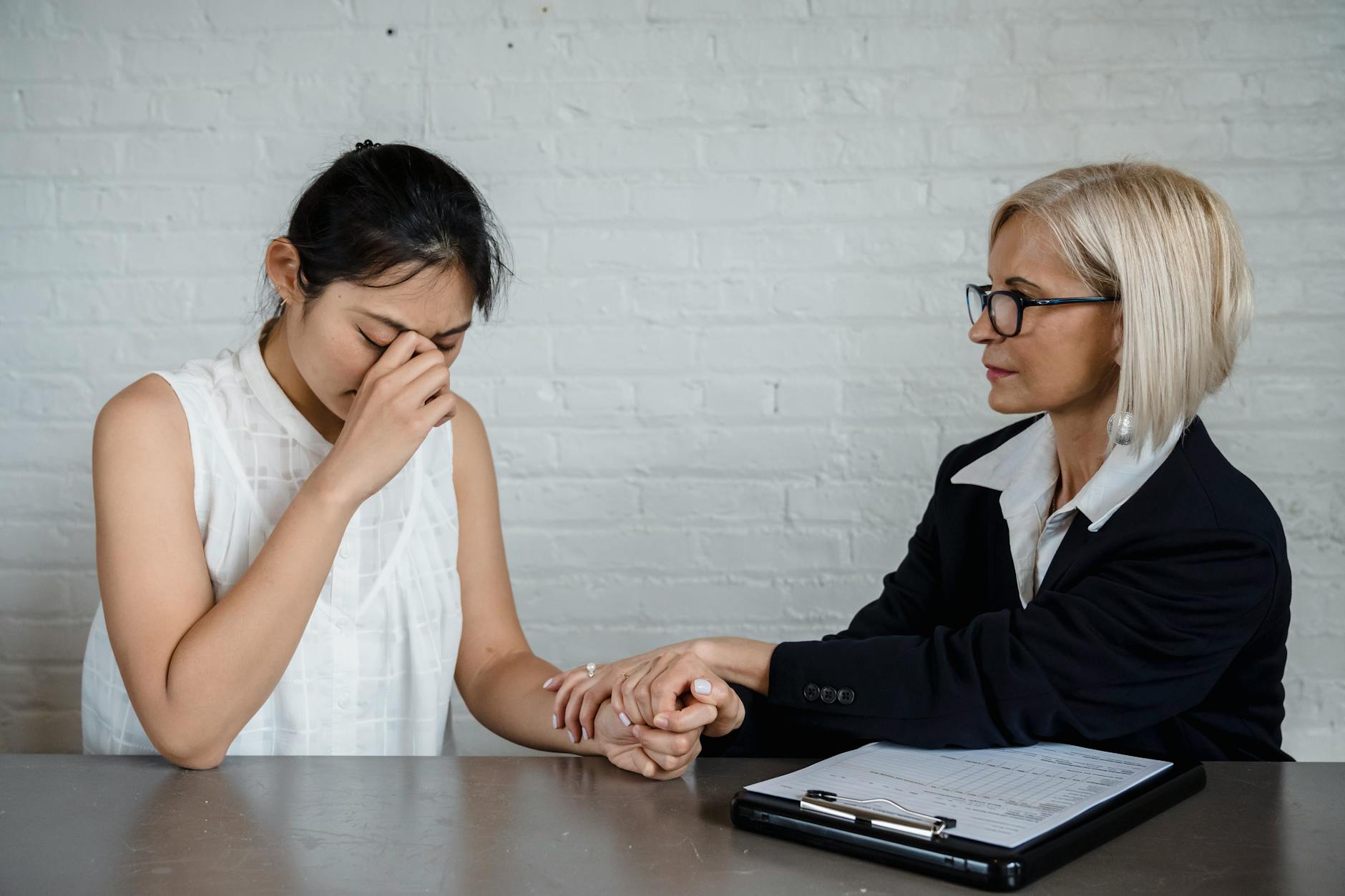A therapist consoles a young woman dealing with emotional distress in a professional setting. - spring depression help