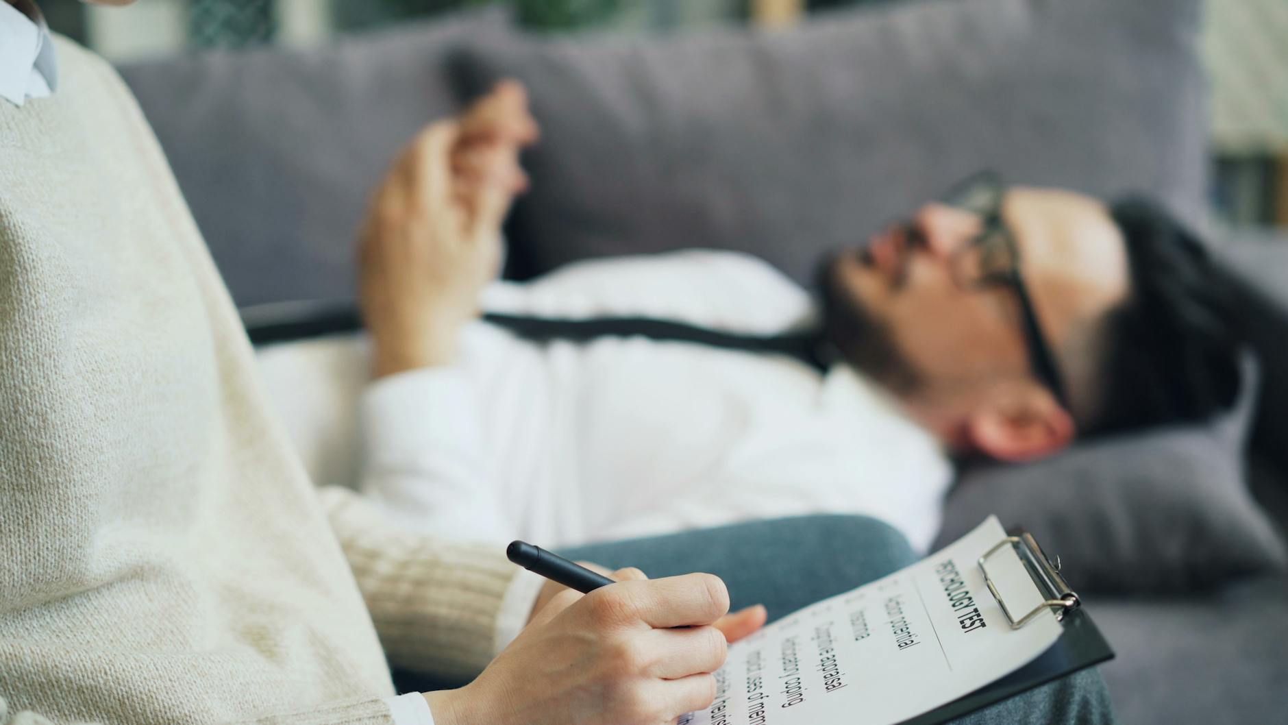 A client discusses issues during a therapy session with a therapist taking notes, indoors. - spring depression therapy