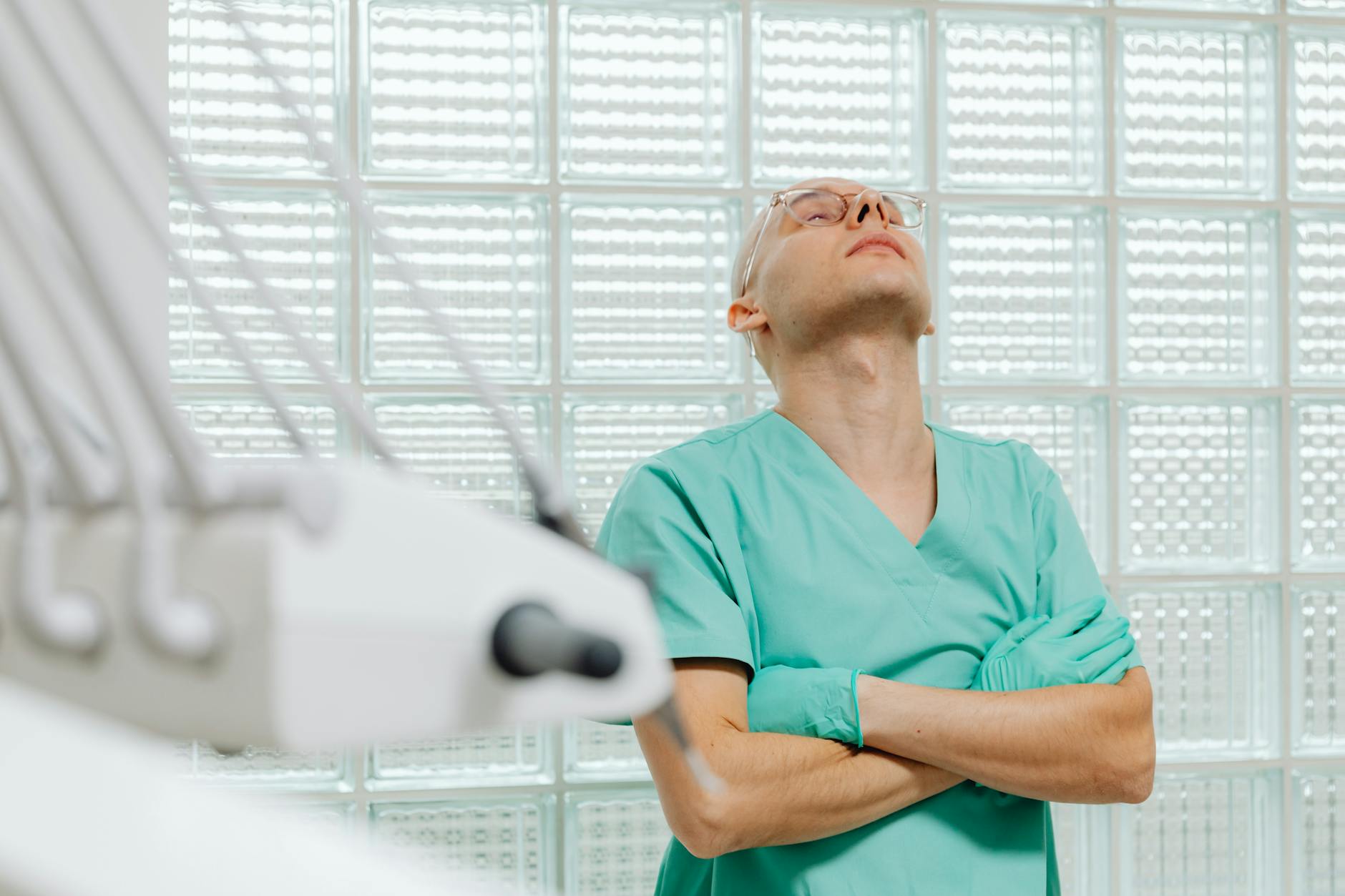 A healthcare worker in scrubs appears exhausted in a medical examination room. - spring fatigue causes