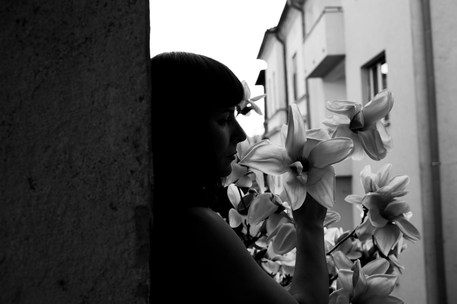 Black and white portrait of a woman contemplating in an urban setting with lilies. - spring melancholy therapy