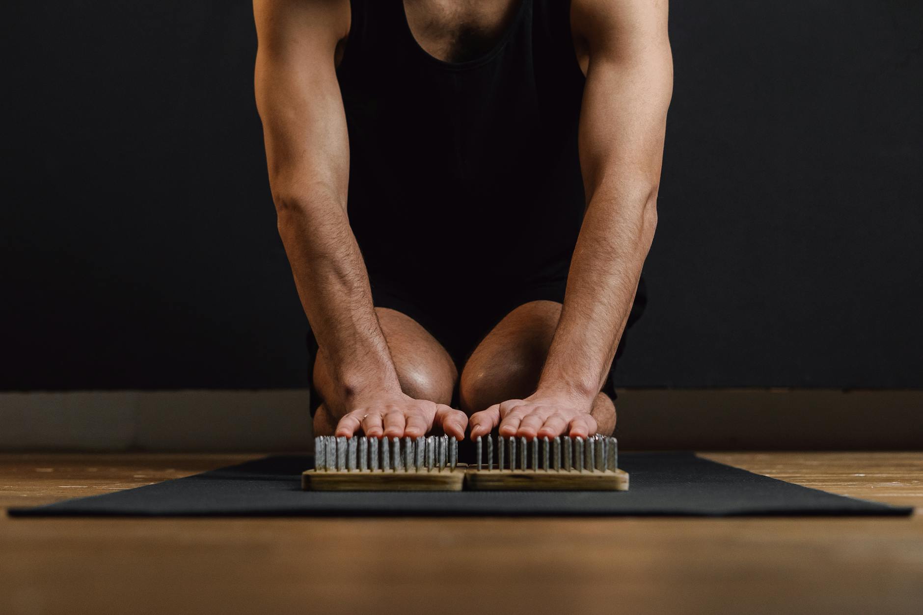 Adult man kneeling on a yoga mat practicing mindfulness with a sadhu board. - spring mindfulness practices