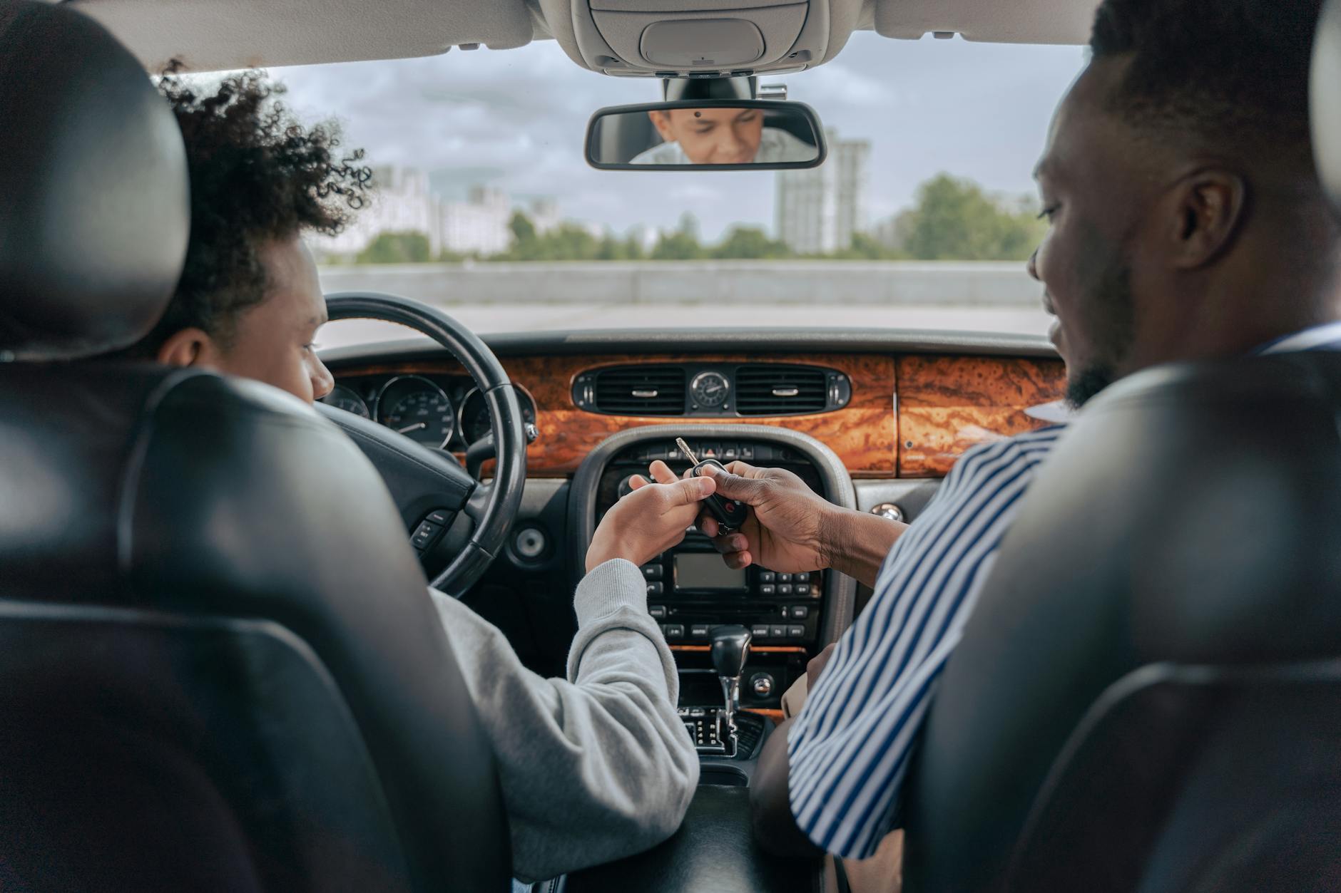 Father and teenage son inside car learning to drive, fostering bonding and guidance. - spring parenting tips