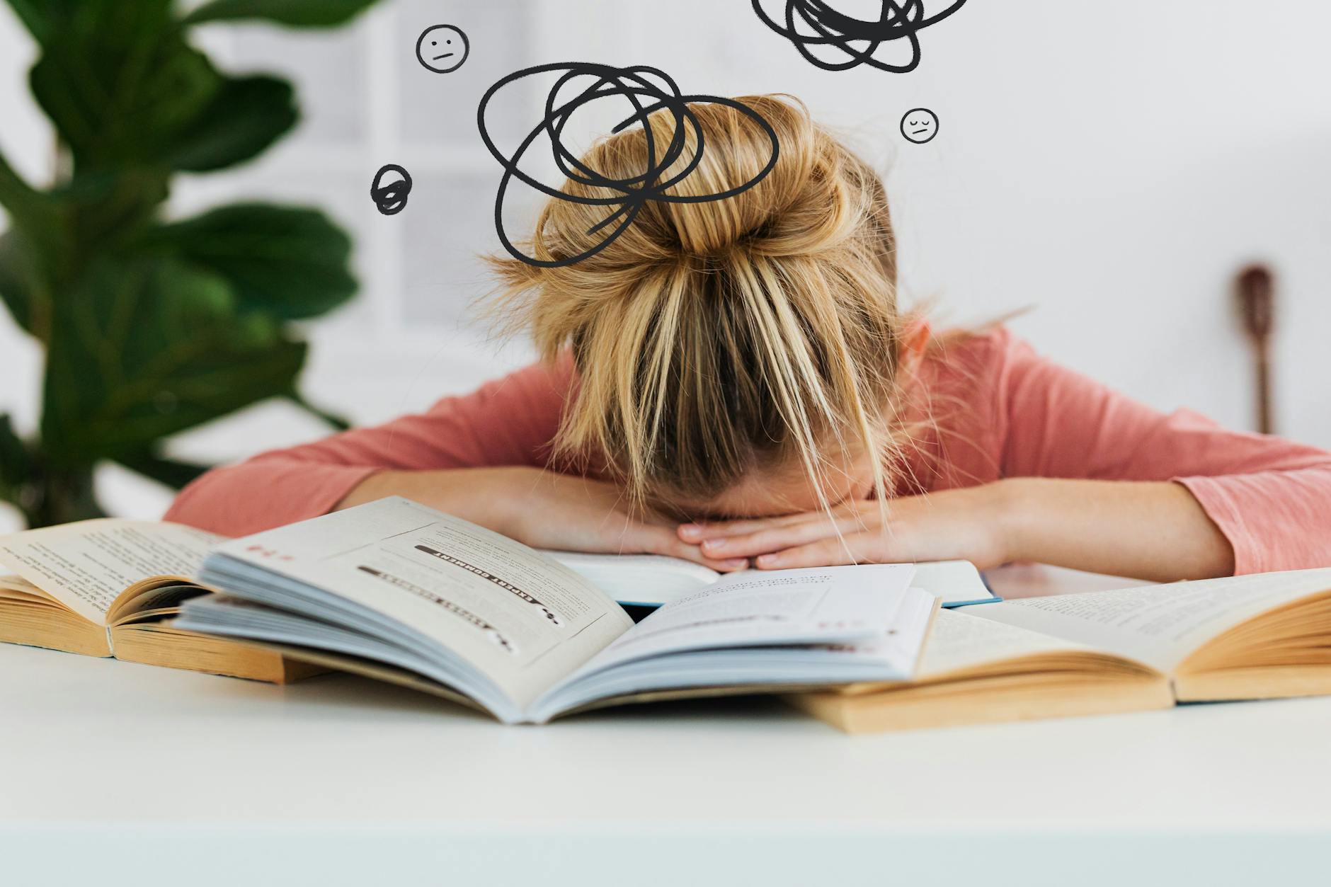 Young woman asleep over books at desk, conveying stress and mental overload. - spring procrastination therapy