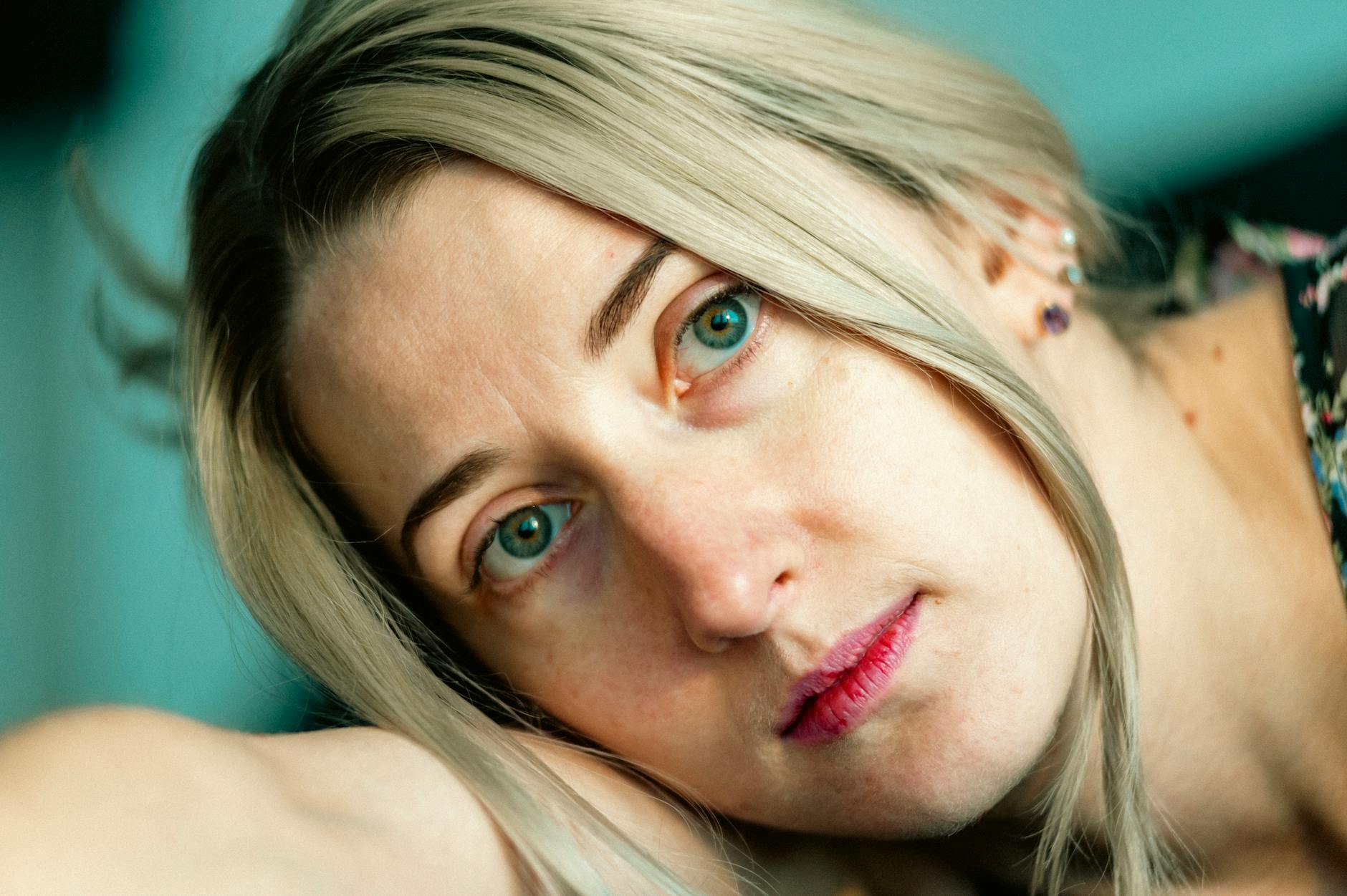 A contemplative close-up portrait of a woman with blonde hair and piercing eyes, indoors. - springtime sadness