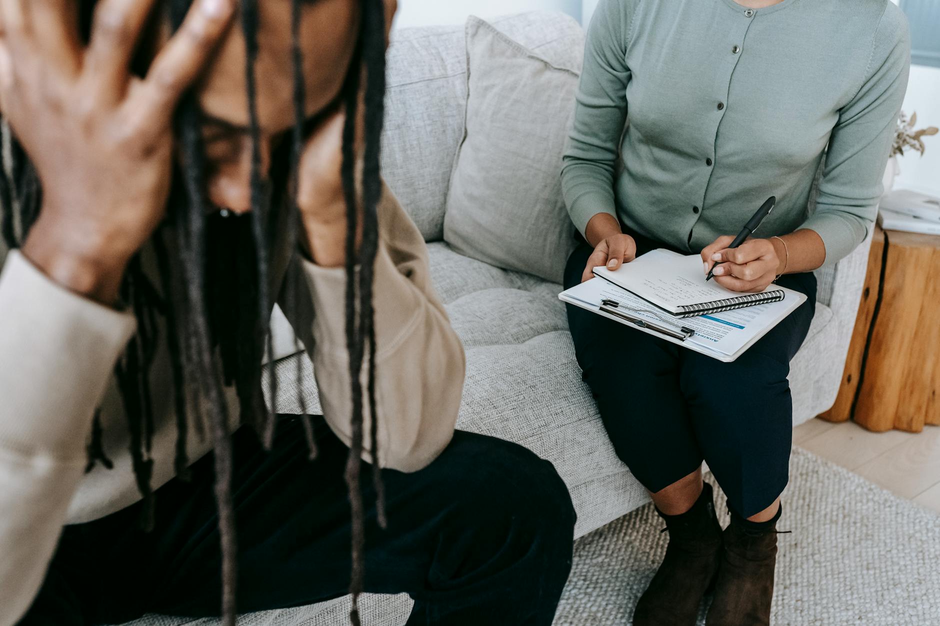 A therapy session showing a concerned patient and a therapist taking notes. - therapist for seasonal anxiety