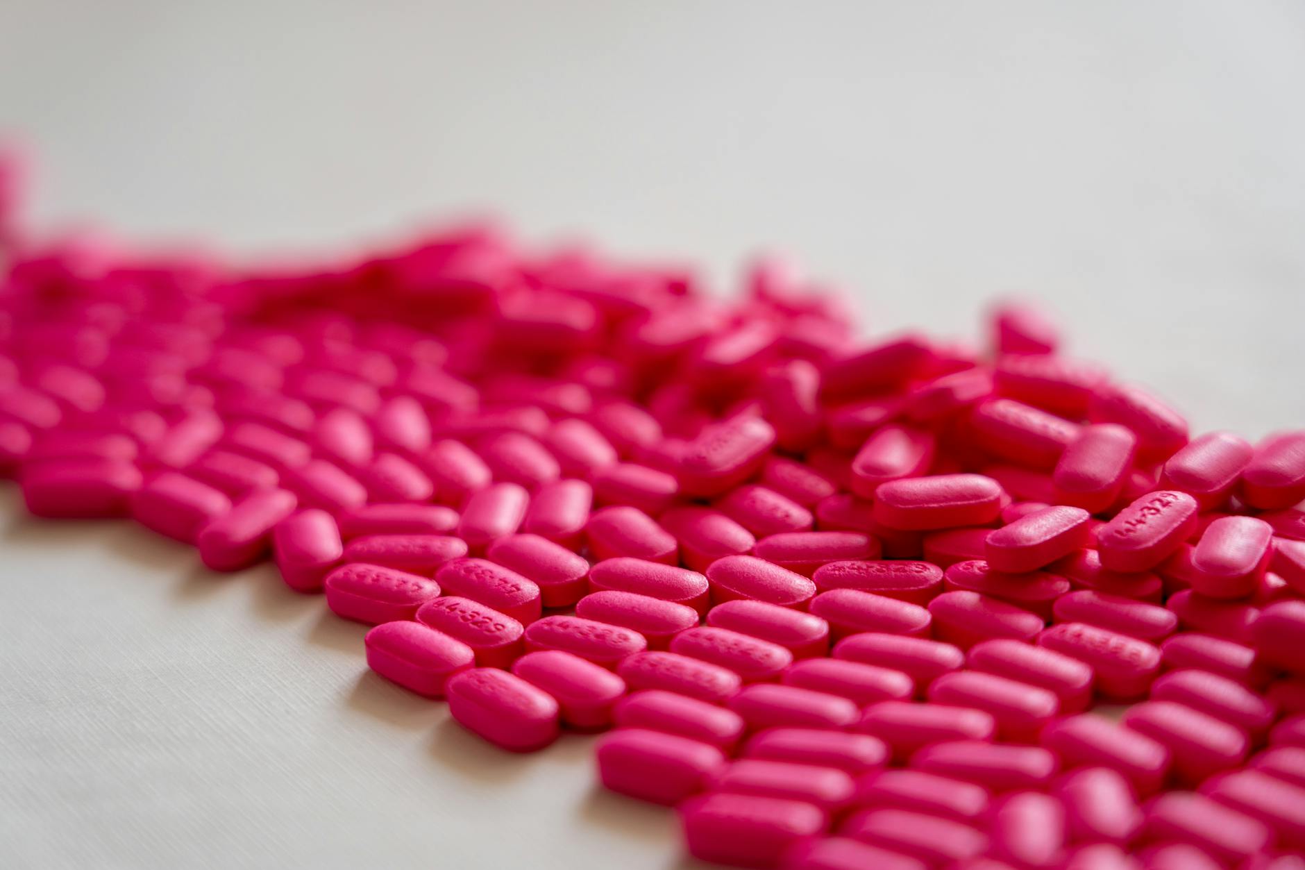 A close-up shot of scattered neon pink pills on a white surface. - toddler spring allergies
