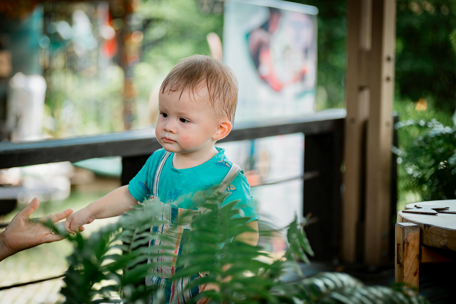 Cute toddler enjoys outdoor adventure surrounded by green plants. - toddler spring energy