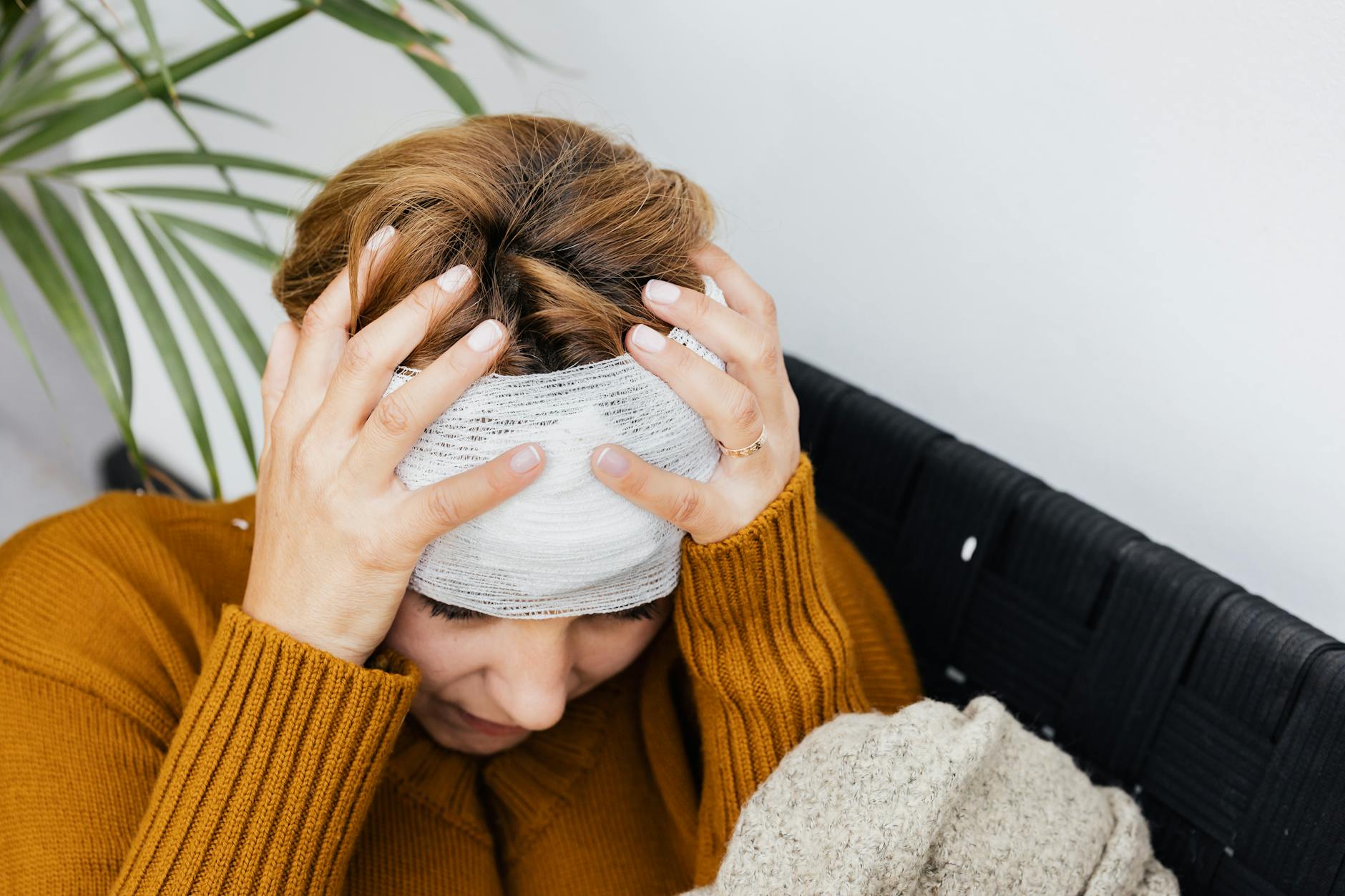 Woman with head injury holding her head in pain indoors. - trauma healing quotes