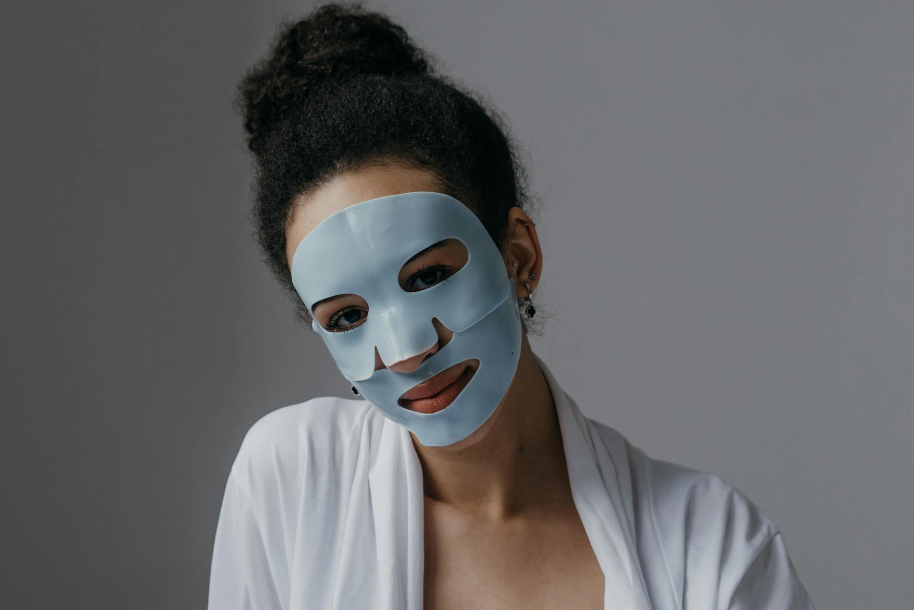 Adult woman enjoying a skincare routine with a blue sheet mask indoors. - winter blues treatment
