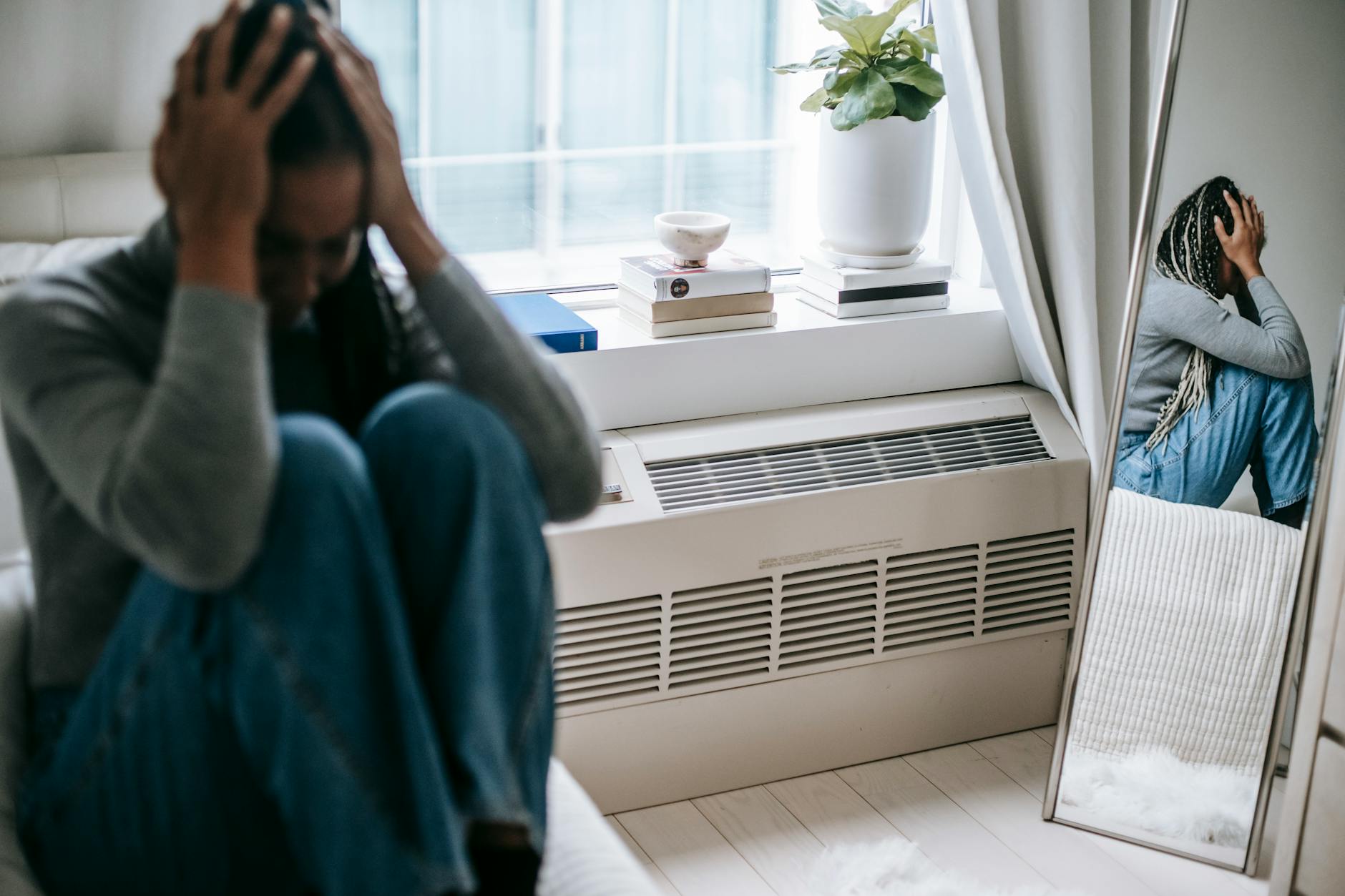 Frustrated young female having mental problem reflecting in mirror while sitting alone in room - winter depression mindfulness