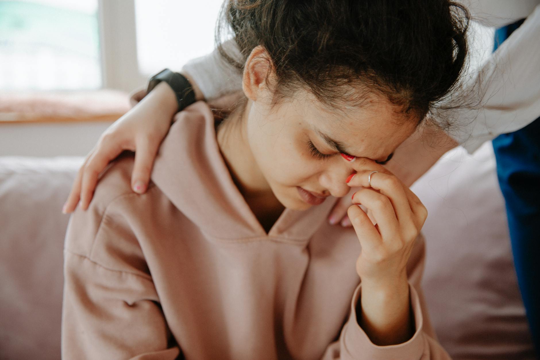 A young woman experiences emotional support from a friend in a comforting embrace. - winter grief therapy