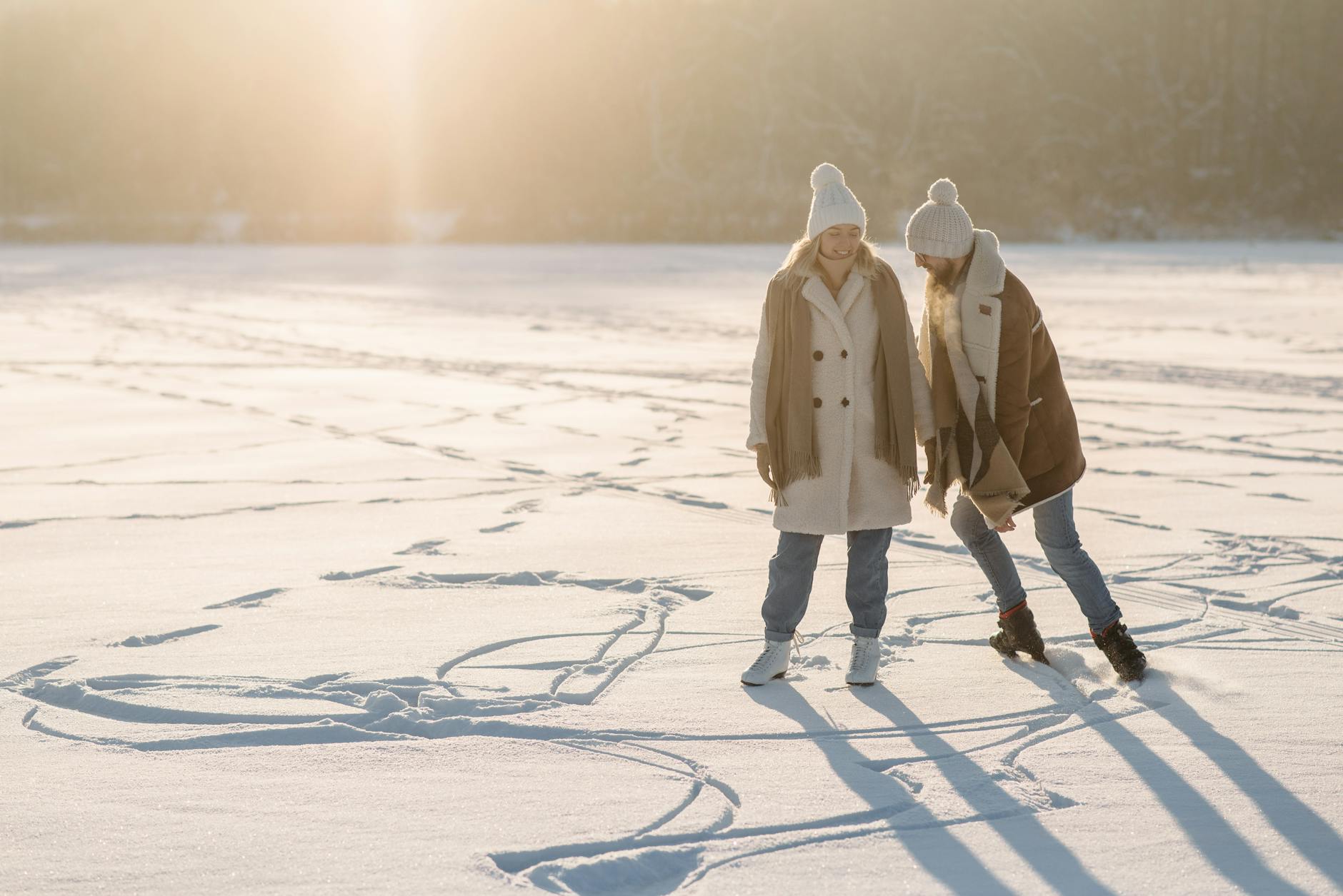Two friends enjoy a sunny winter day, playfully making snow angels on a vast snowy field. - winter relationship activities