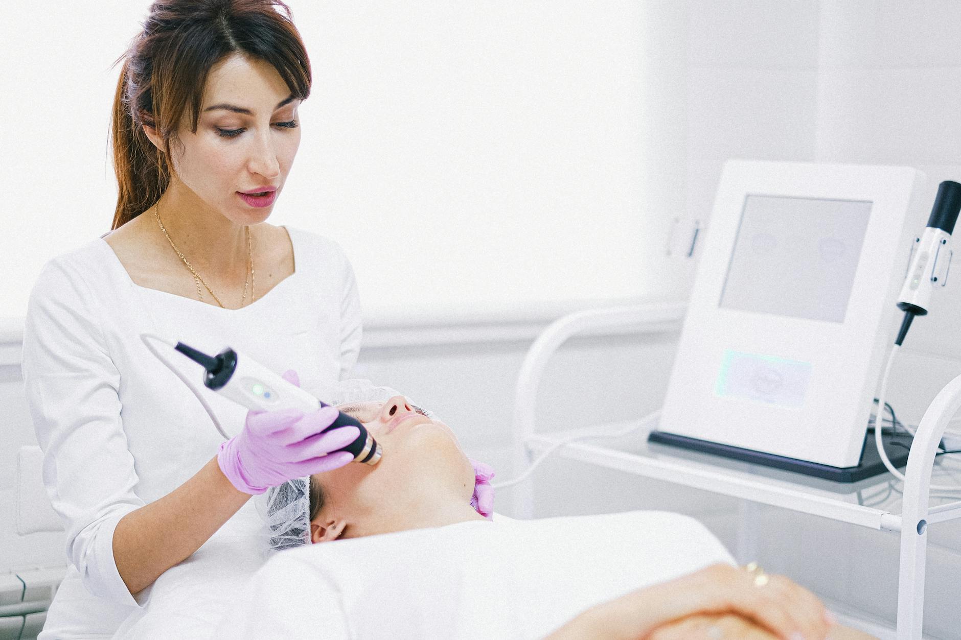 Aesthetician providing a laser facial treatment to a patient in a spa clinic setting. - winter sluggishness treatment