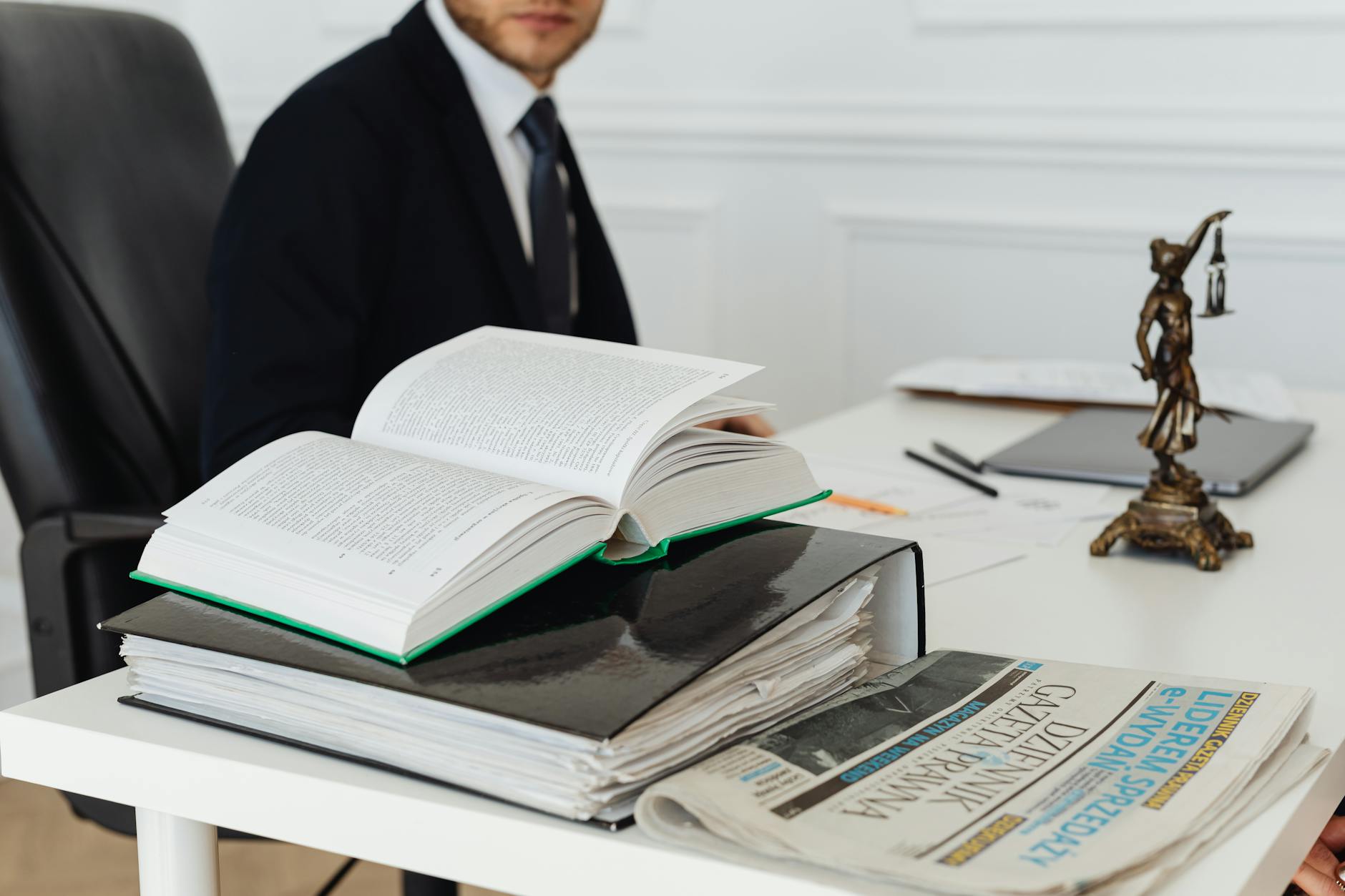 A lawyer sitting at a desk with legal books, documents, and a newspaper, embodying professionalism. - are workplace relationships legal