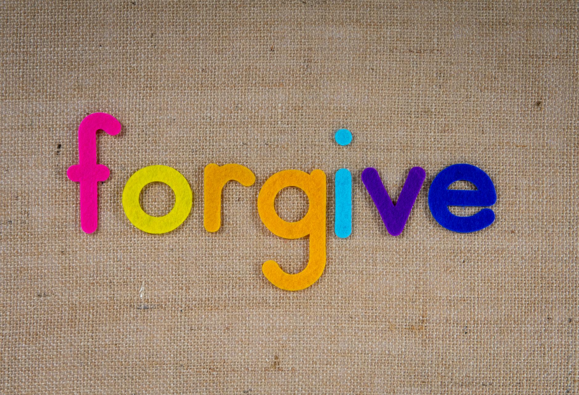 Vibrant felt letters spelling 'forgive' on a burlap background. - what does apologize mean