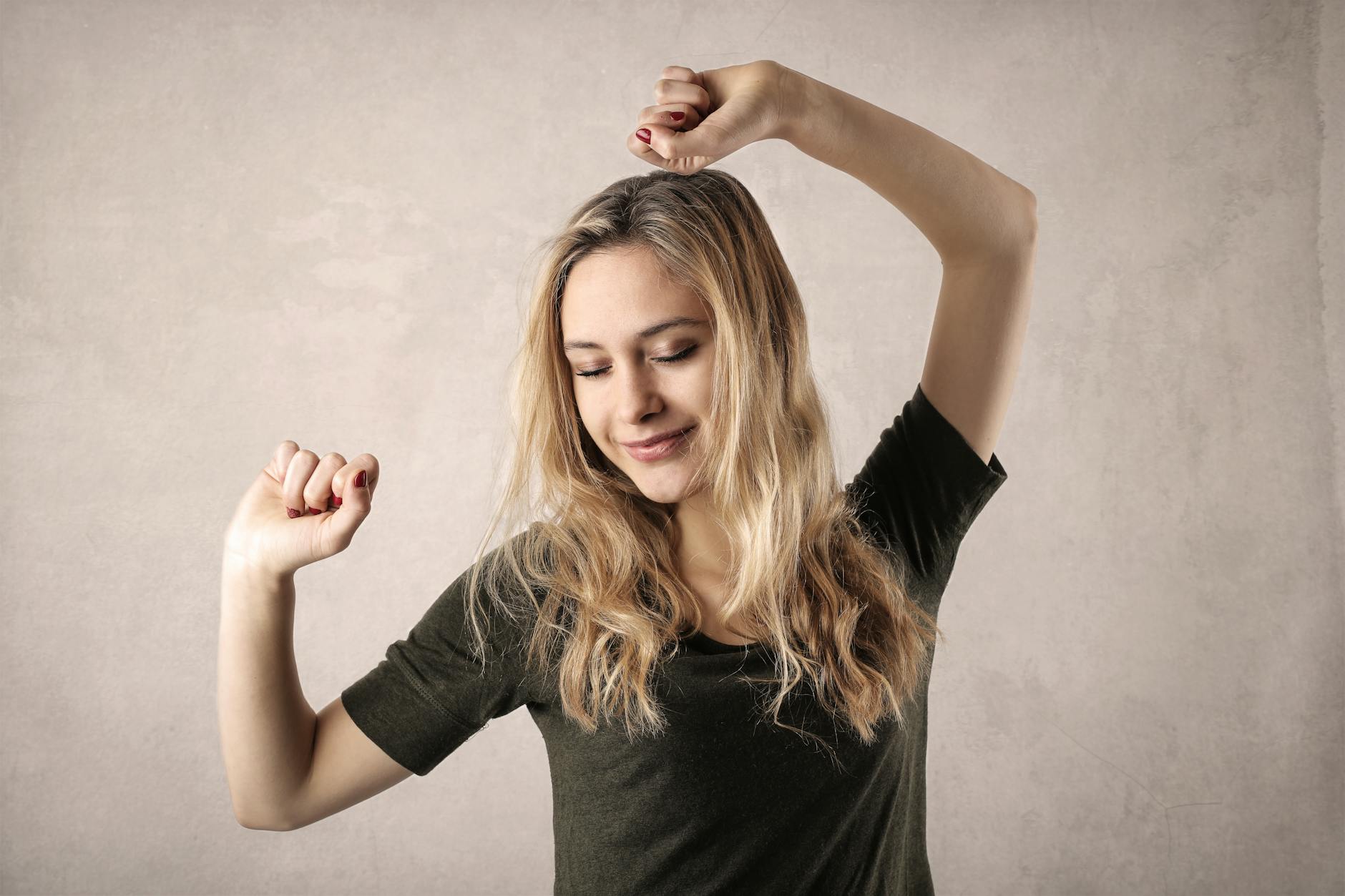 Happy young woman with blond hair dancing with joy, showcasing casual style indoors. - boost mood naturally