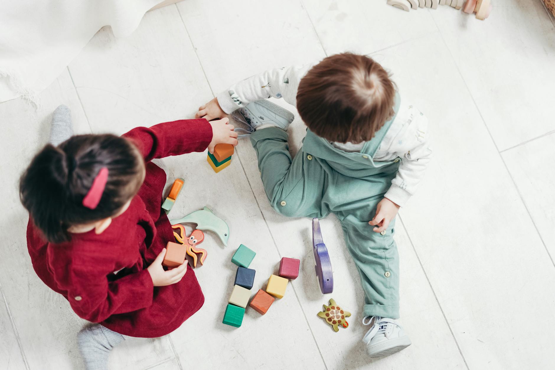 Two young children engaging with colorful wooden blocks indoors, fostering creativity and fun. - child social skills