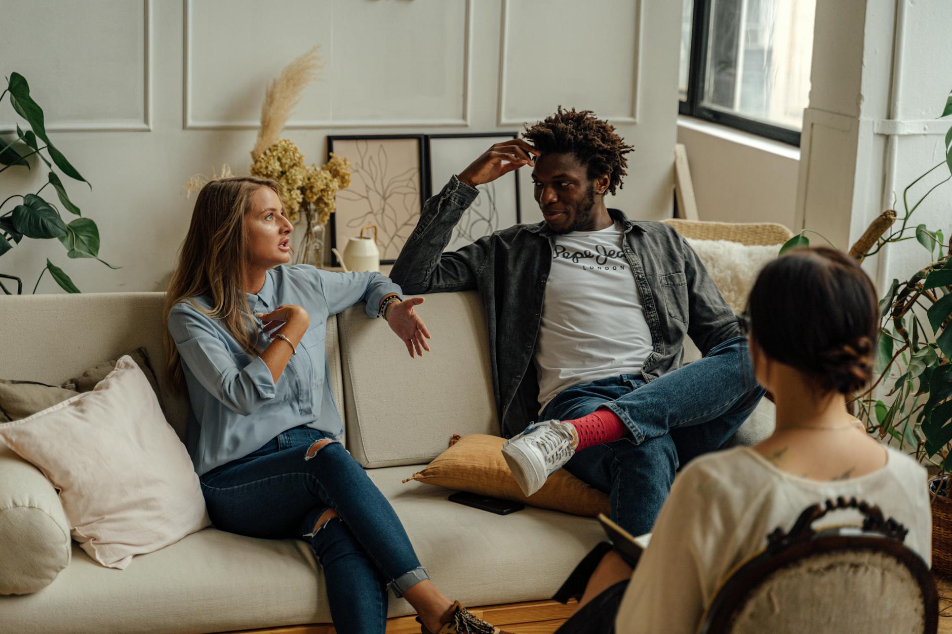 A couple is engaged in a lively conversation during a therapy session with a counselor. - couples counseling benefits