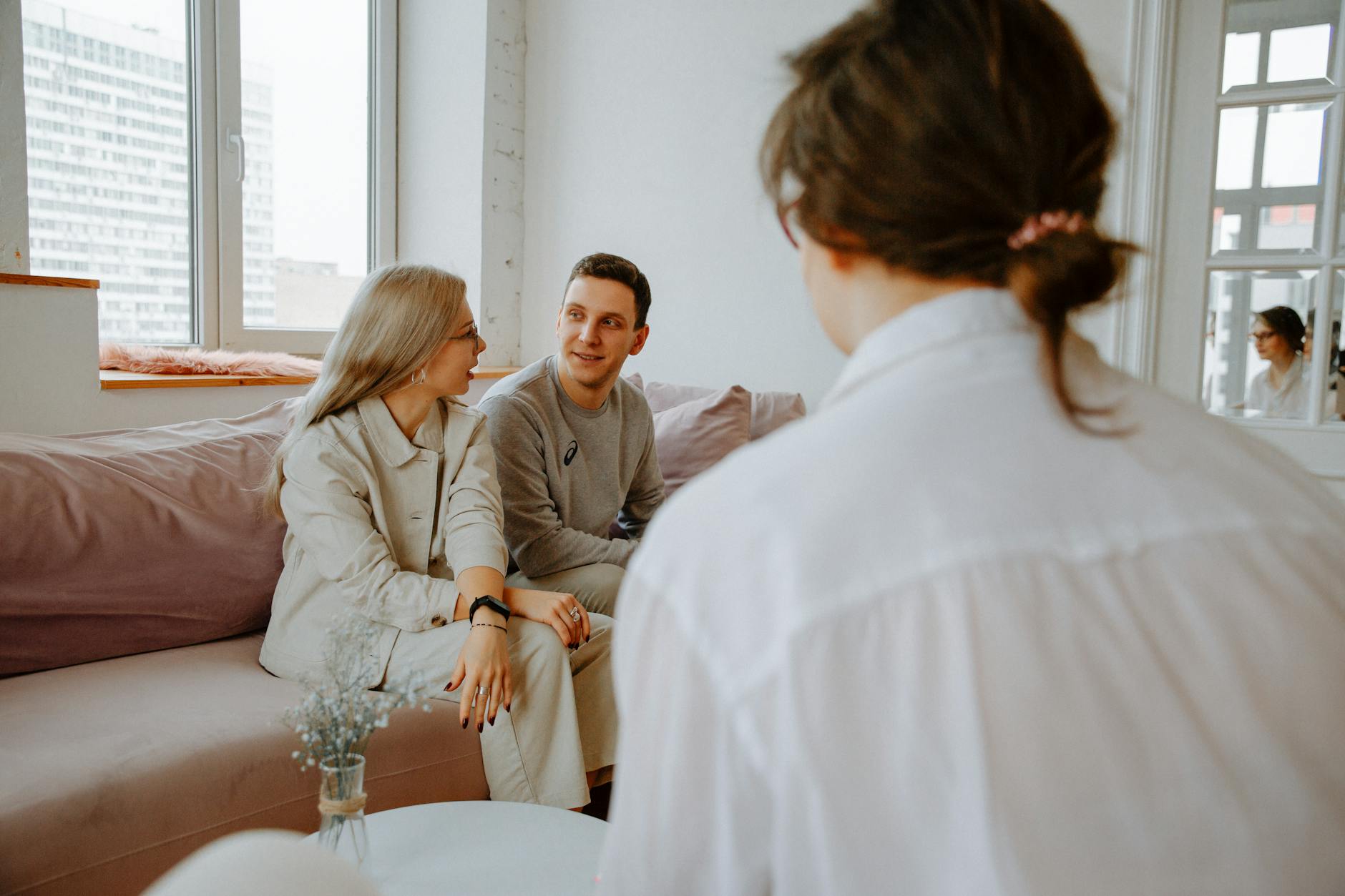 A couple engaged in a counseling session with a therapist in a modern indoor setting. - couples therapy benefits